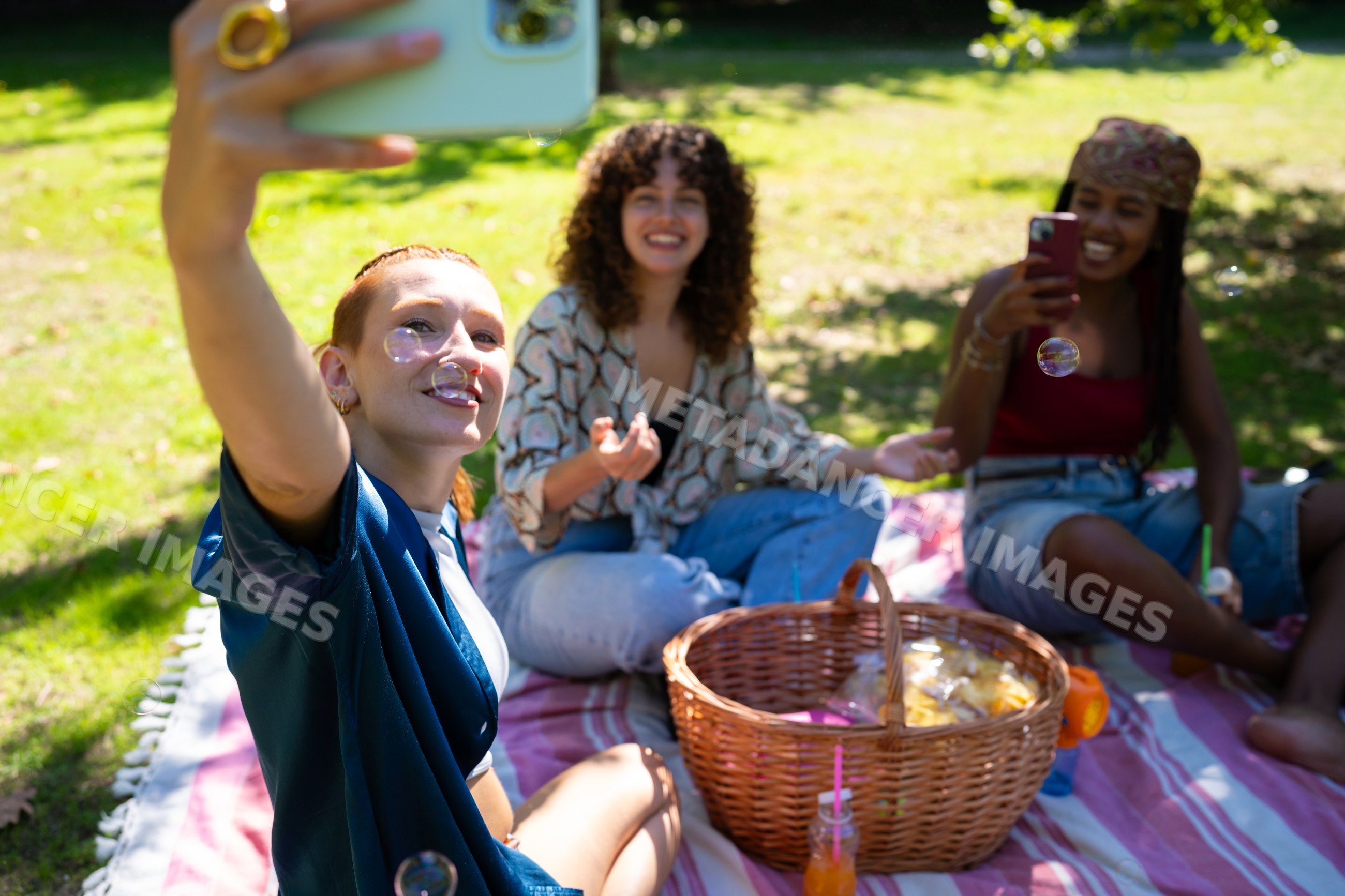 Friends enjoying picnic and selfies outdoors on a sunny day