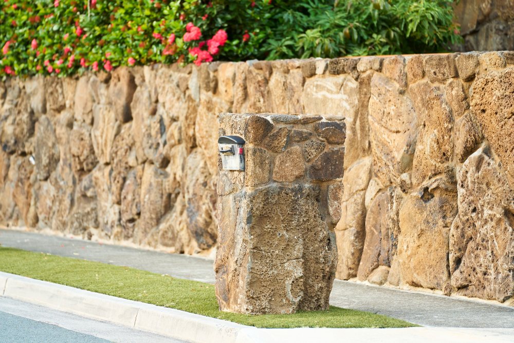 Stone mailbox with natural rock construction beside stone wall on Oahu