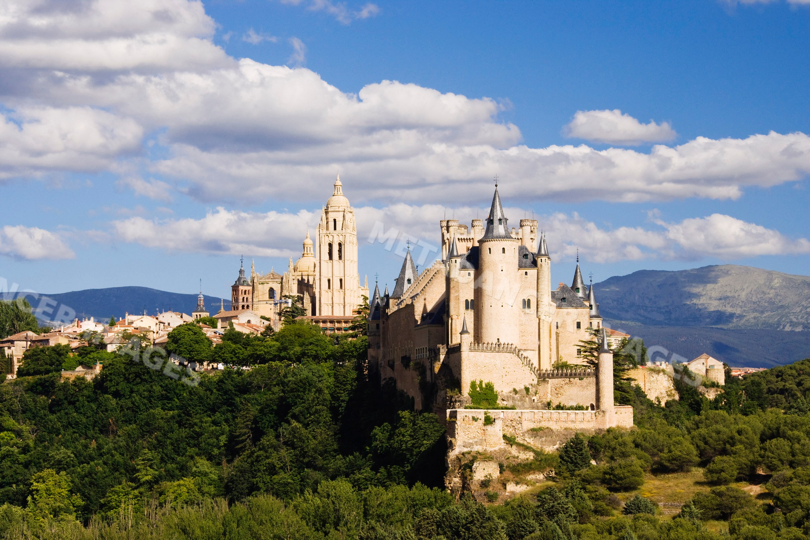 Alcazar castle on hilltop surrounded by trees in Spain