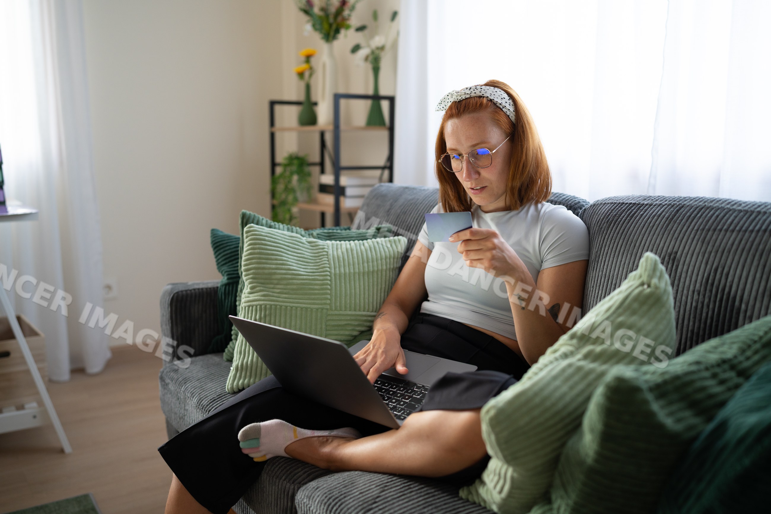 A white woman shopping online with a credit card and laptop at home
