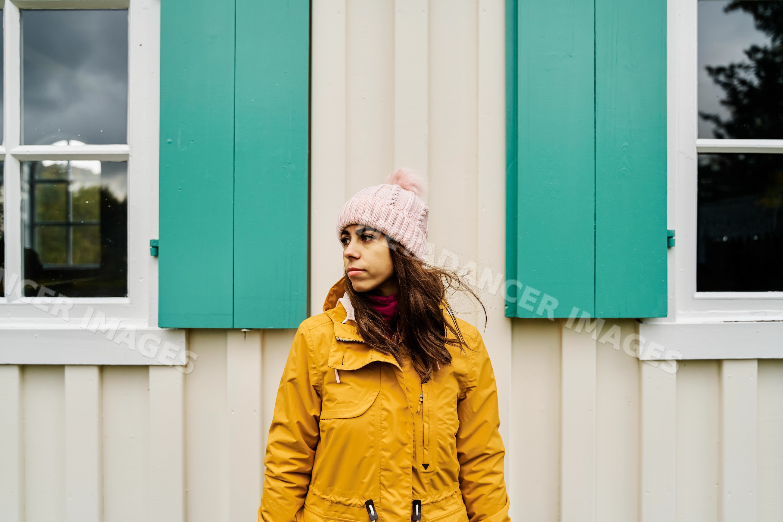 White Woman standing outdoors wearing yellow jacket and pink knit hat