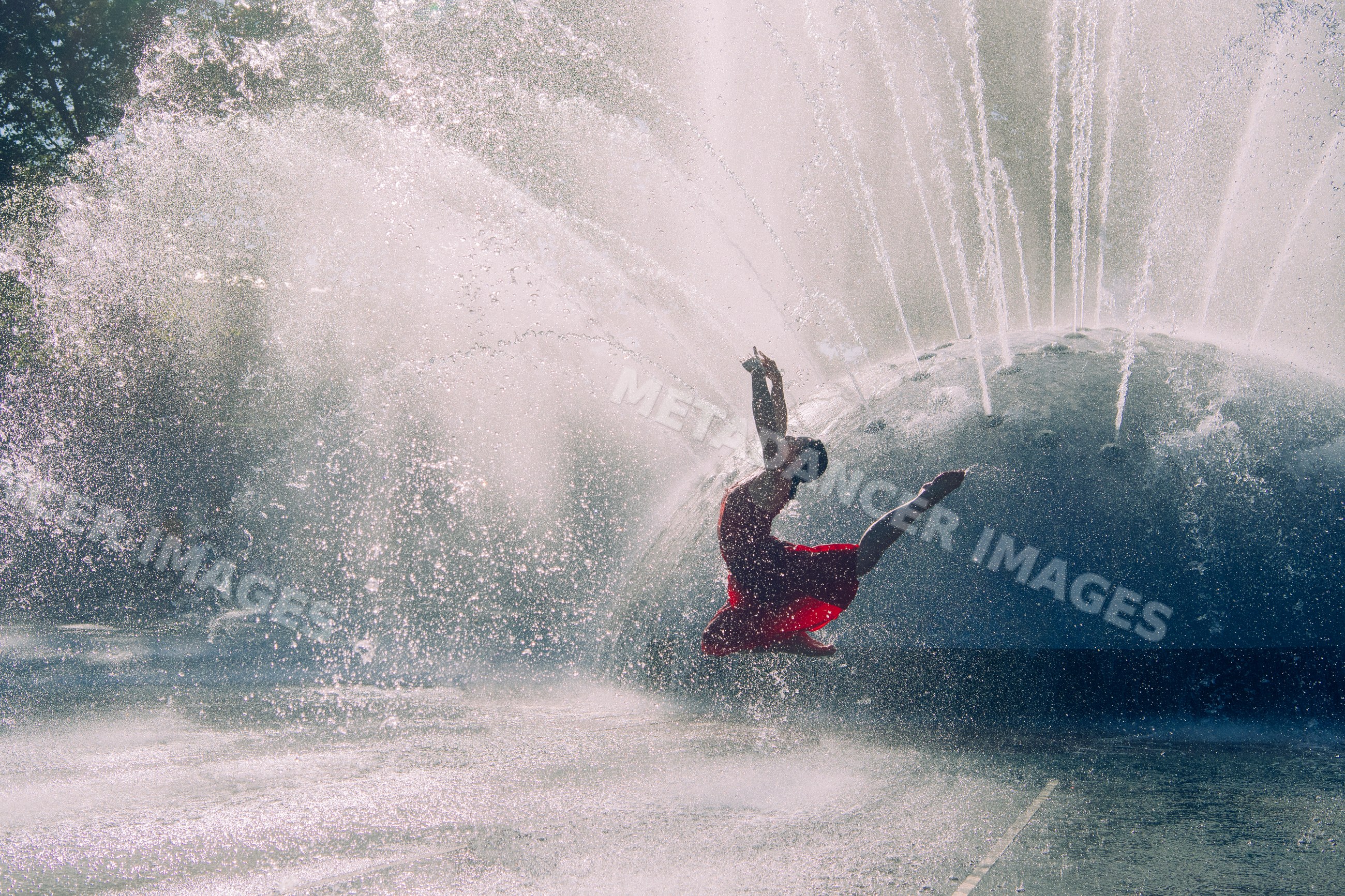 White dancer leaping near water fountain splashes outdoors