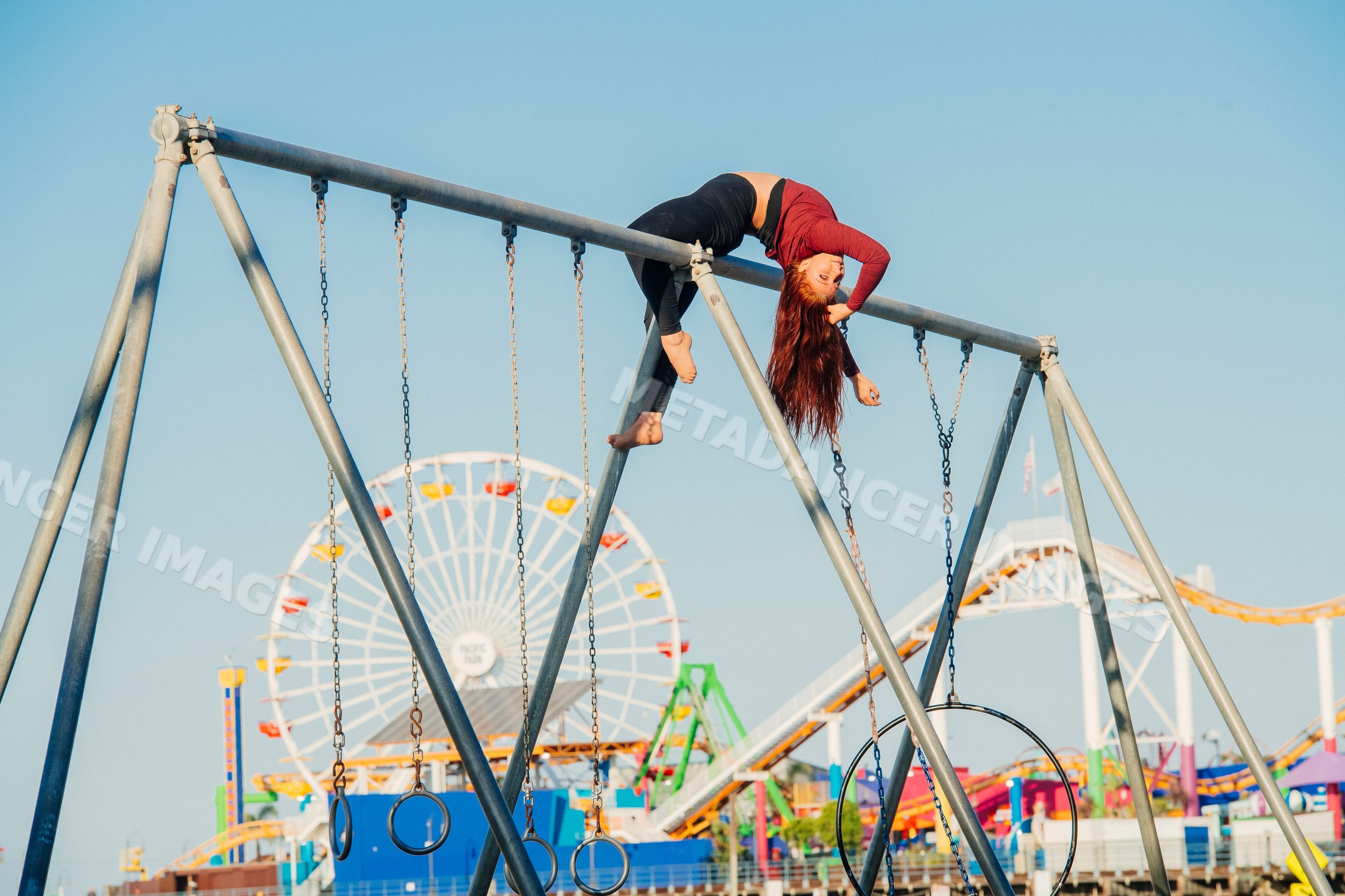 White woman hanging upside down on swing set with amusement park rides