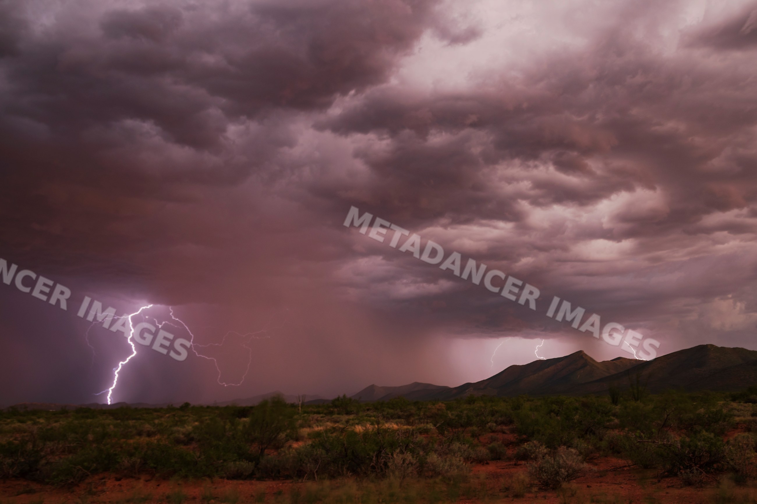 Lightning striking over desert storm with mountains