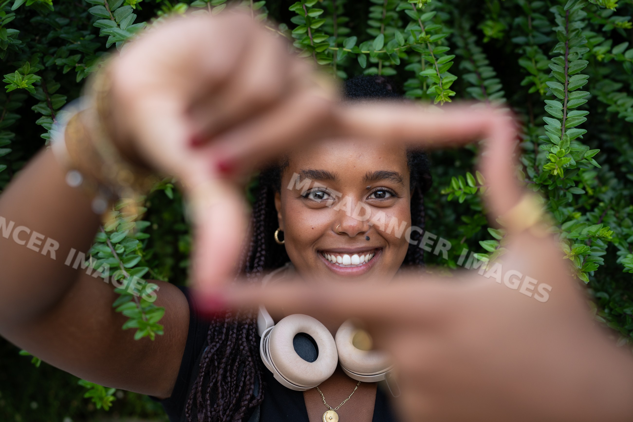 A smiling African American woman with braided hair frames her face