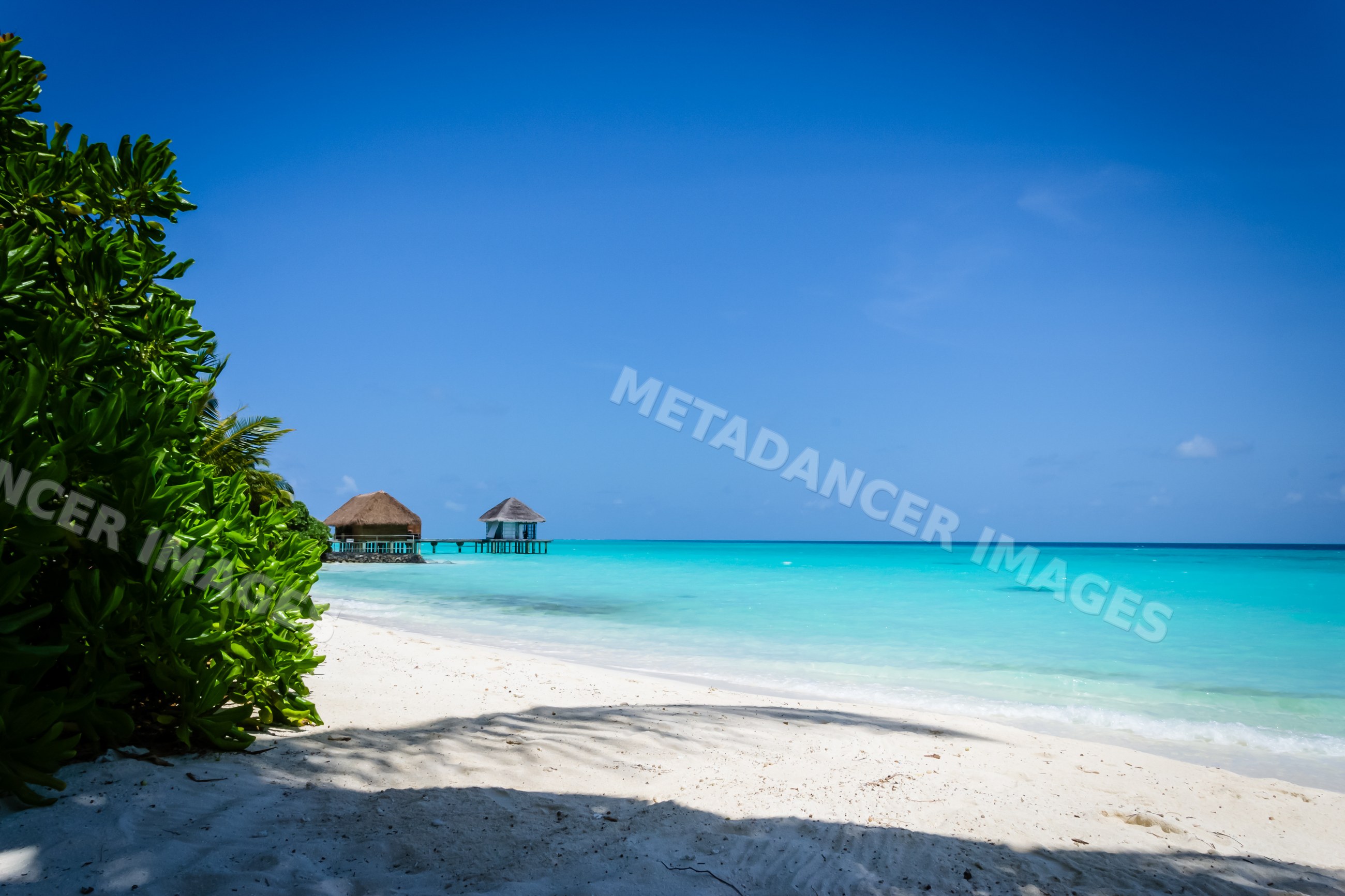 Beach with turquoise water and overwater huts in a beach