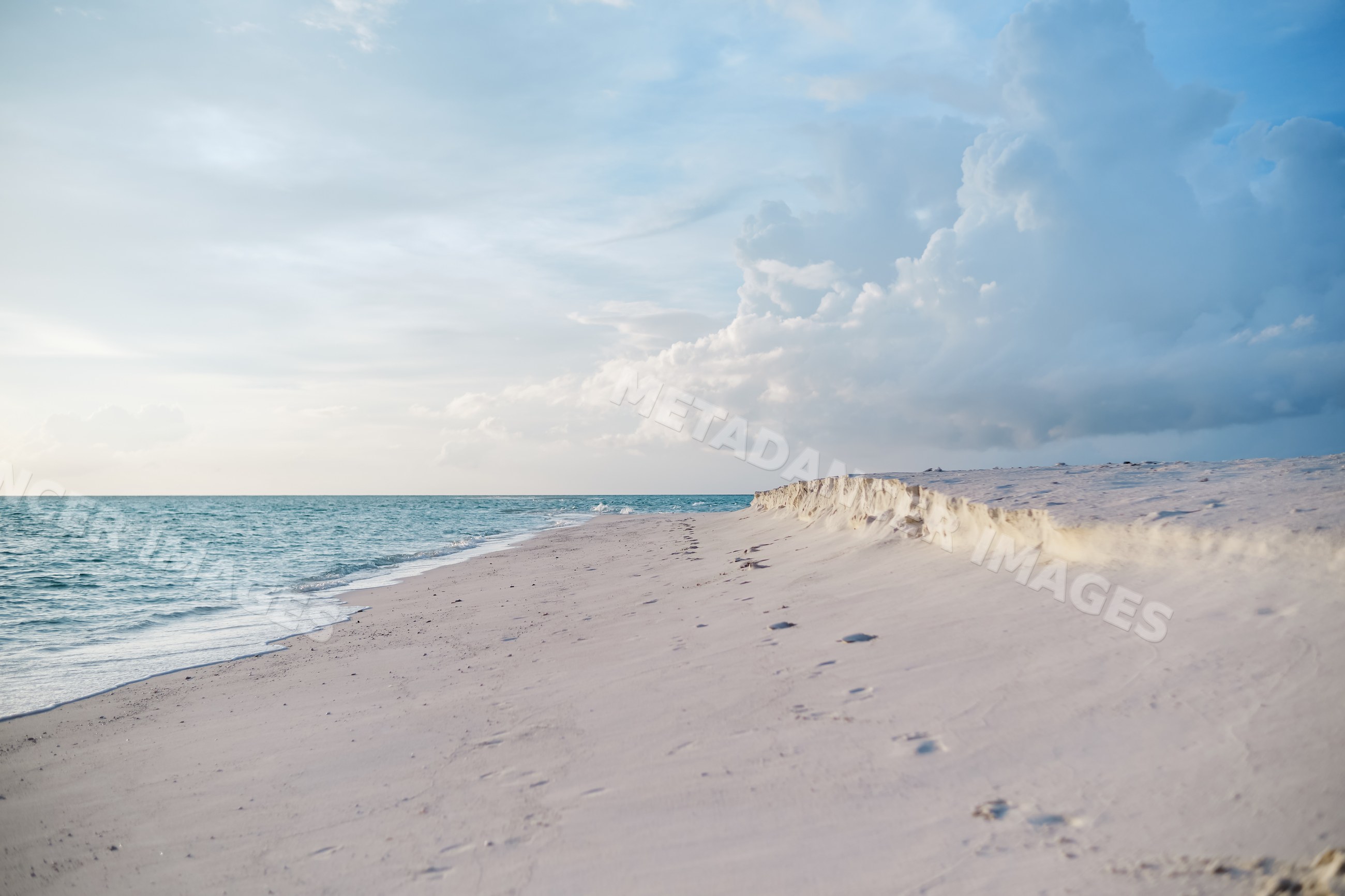 A serene sandy beach with footprints along the shoreline in a beach
