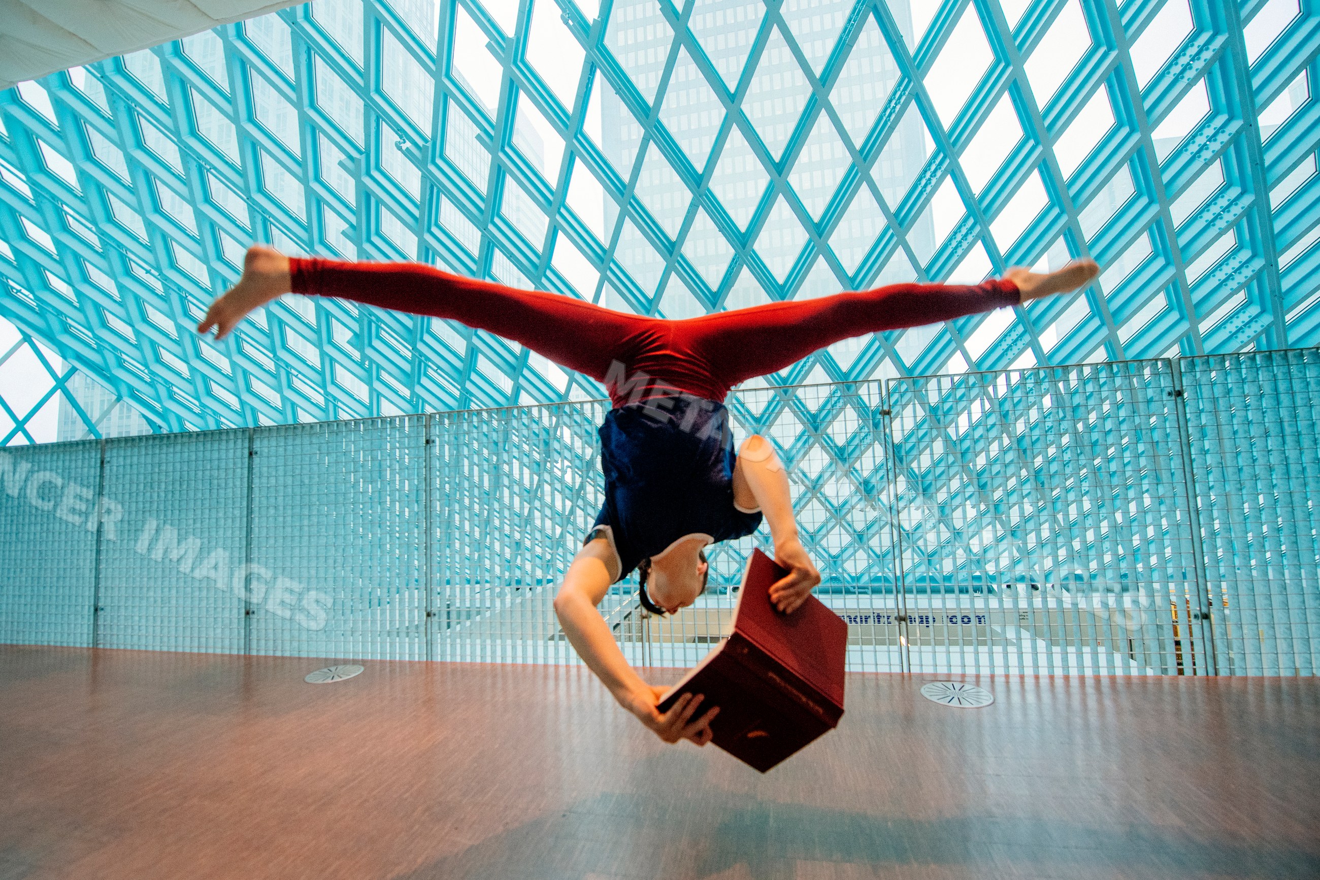 A person does a handstand reading a book inside Seattle public library