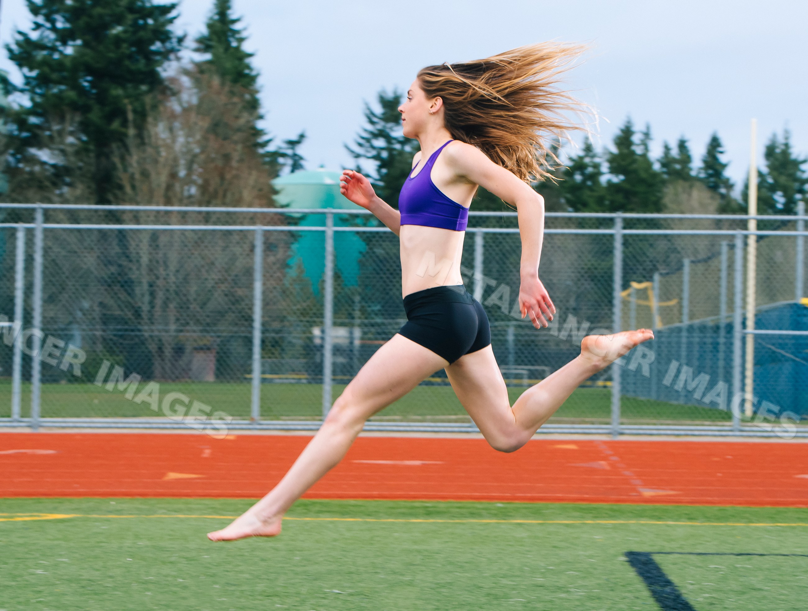 White woman running barefoot on outdoor track field