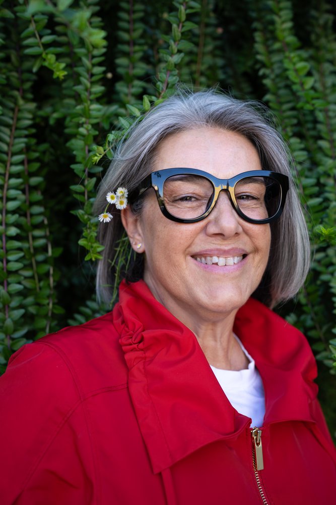 Smiling white woman in red jacket with flower in hair outdoors