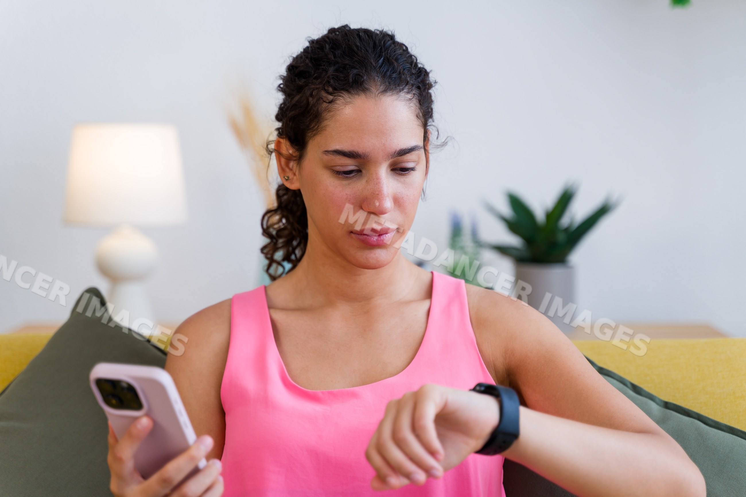 A Hispanic woman checks the time on her smartwatch