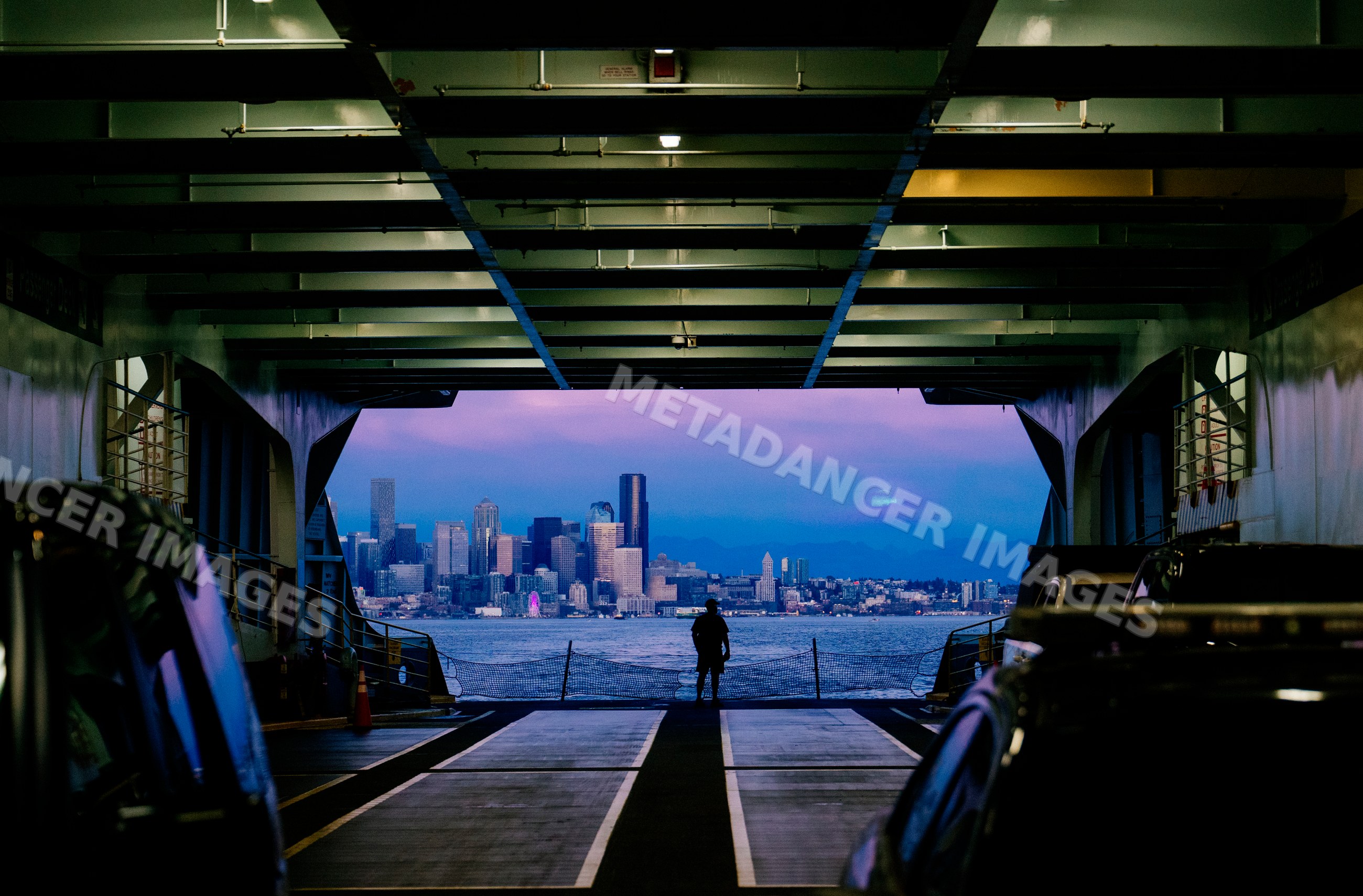White person silhouette on ferry deck with city skyline at dusk