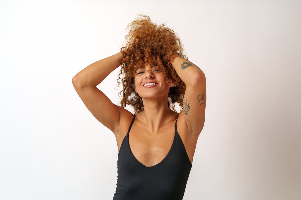 Confident Hispanic woman with curly hair and tattoos posing