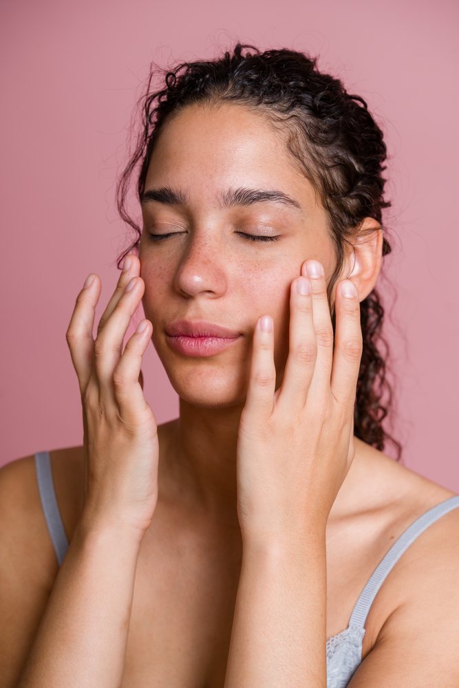 Hispanic woman massaging face with closed eyes