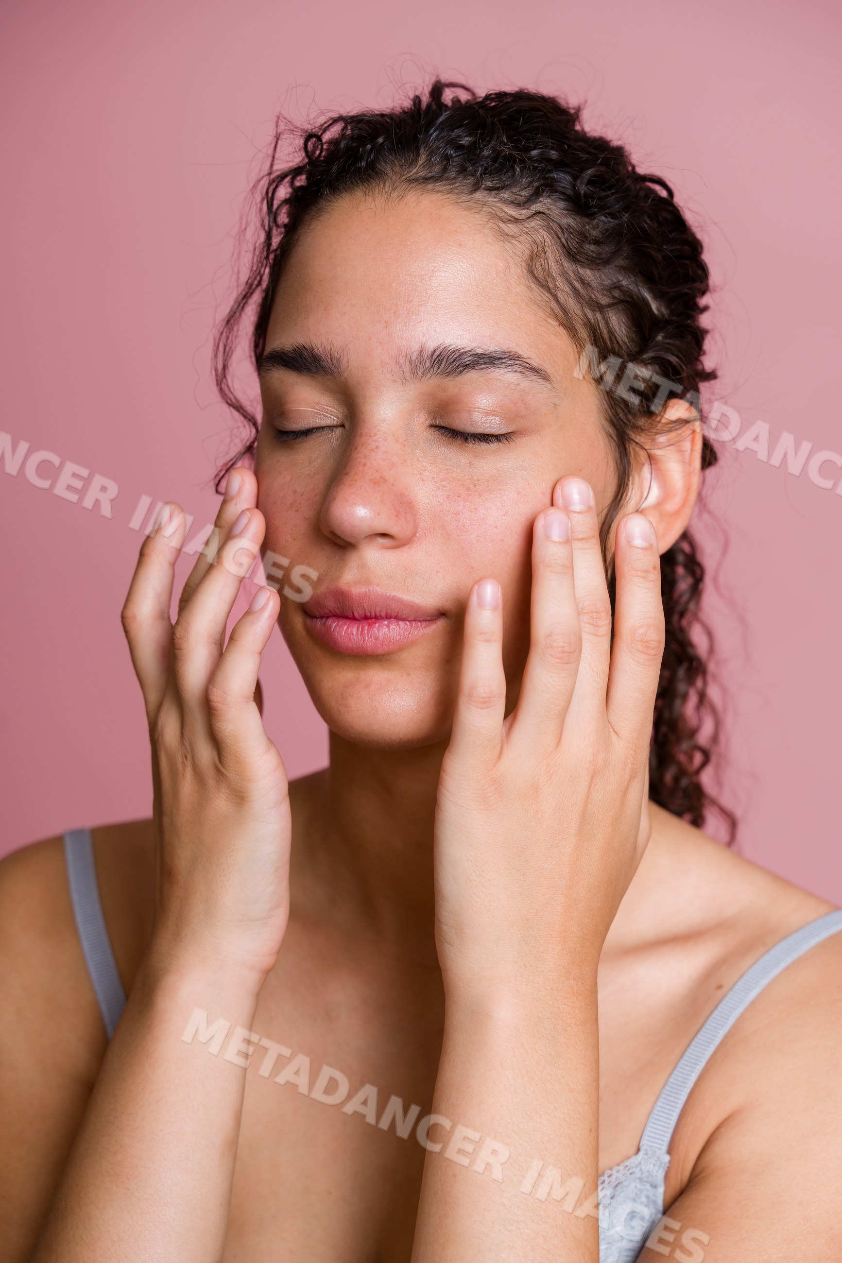 Hispanic woman massaging face with closed eyes