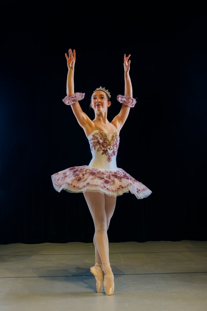 A ballerina performs a classical ballet pose during a stage production