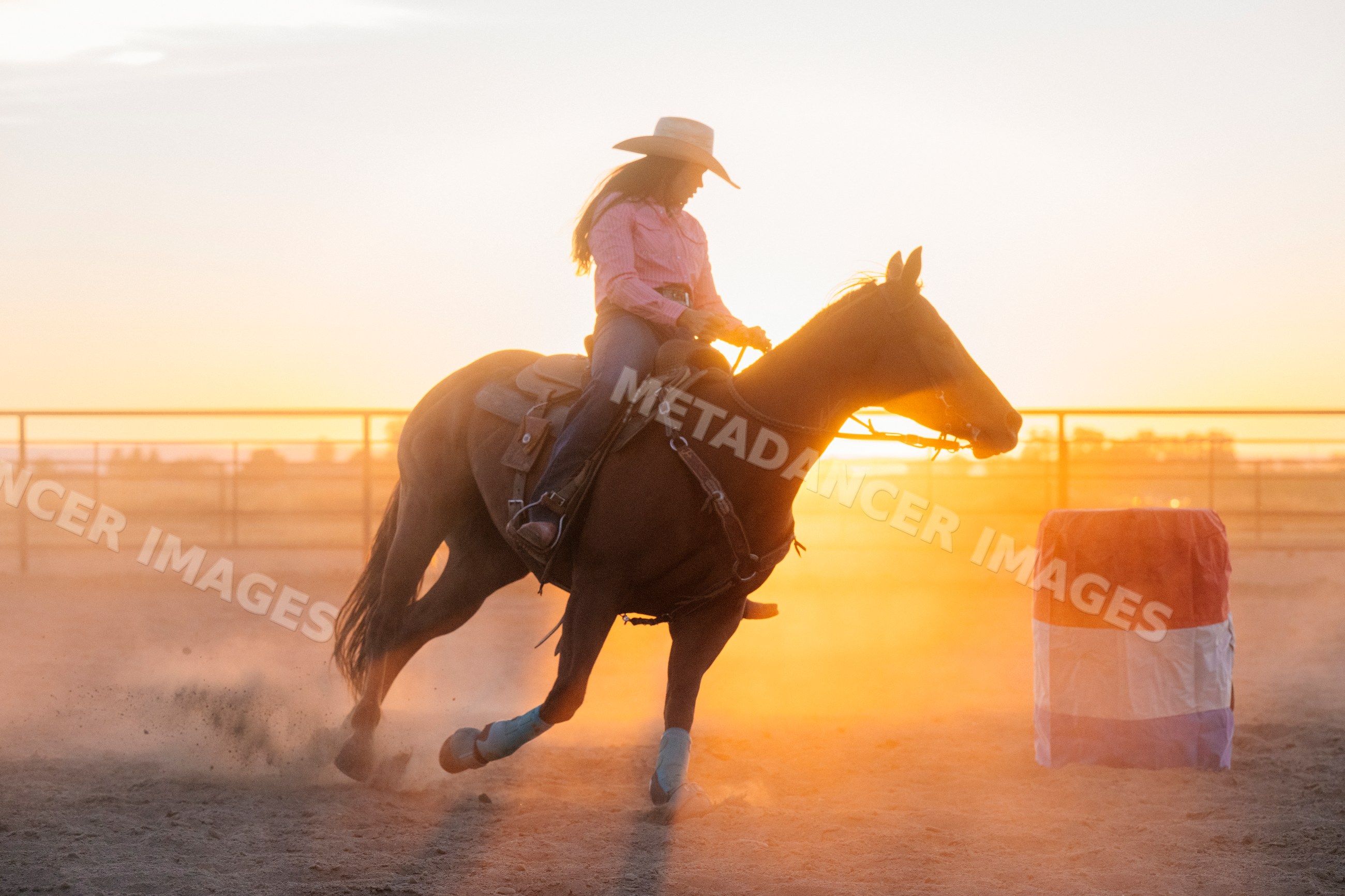 Horse and rider turning around barrel at sunset in Southwest USA arena