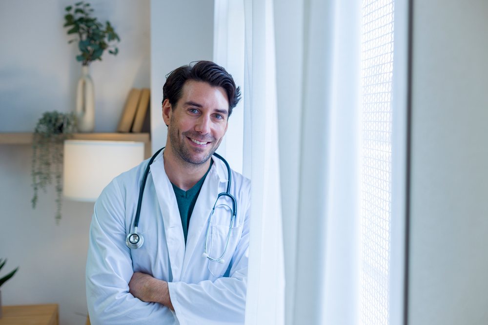 Male doctor smiling in hospital room by window light