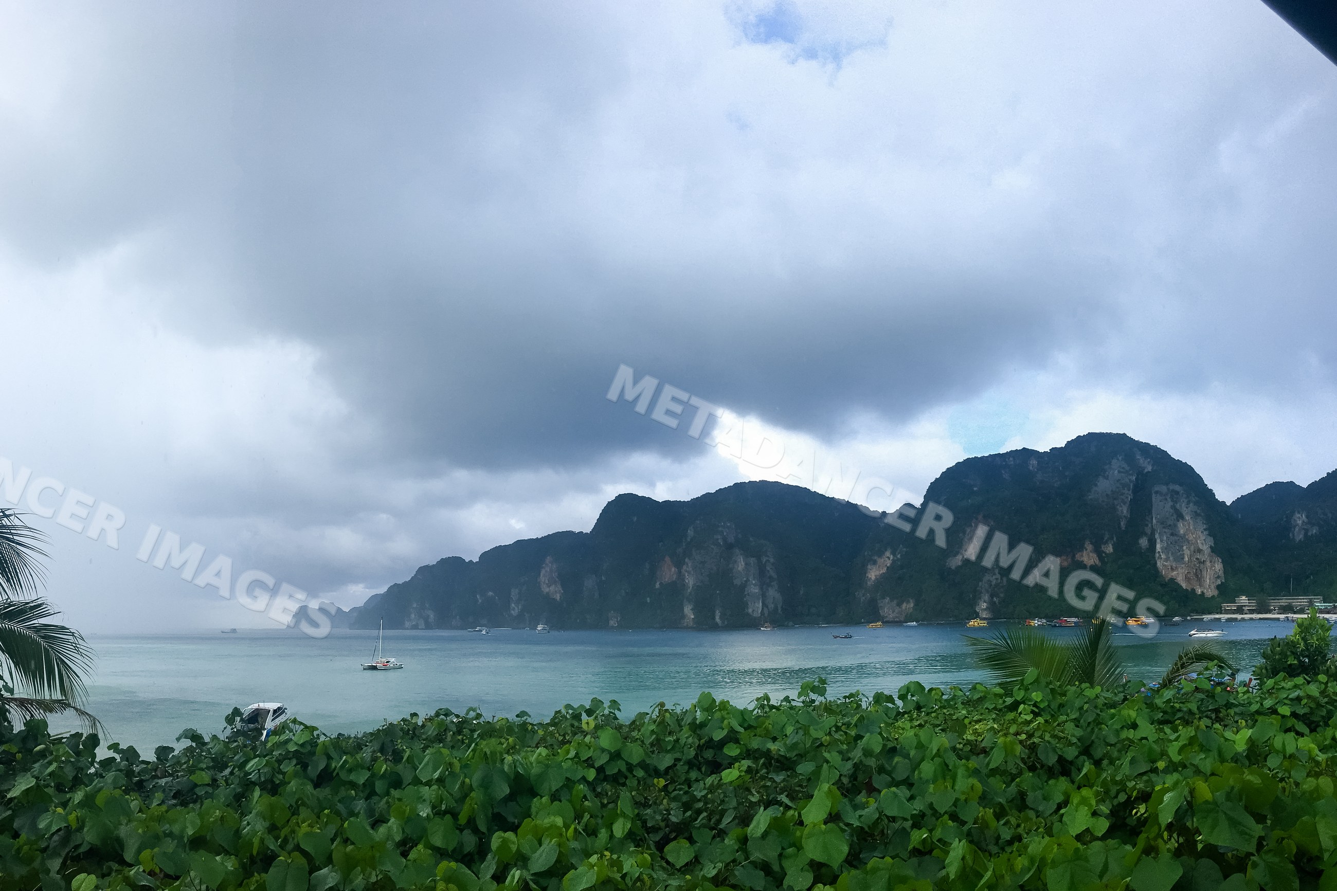 Tropical coastline with boats under cloudy sky