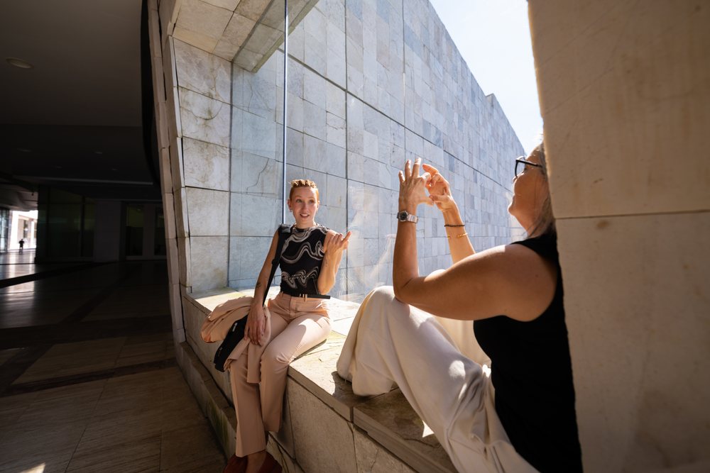 Two white women conversing on a window ledge