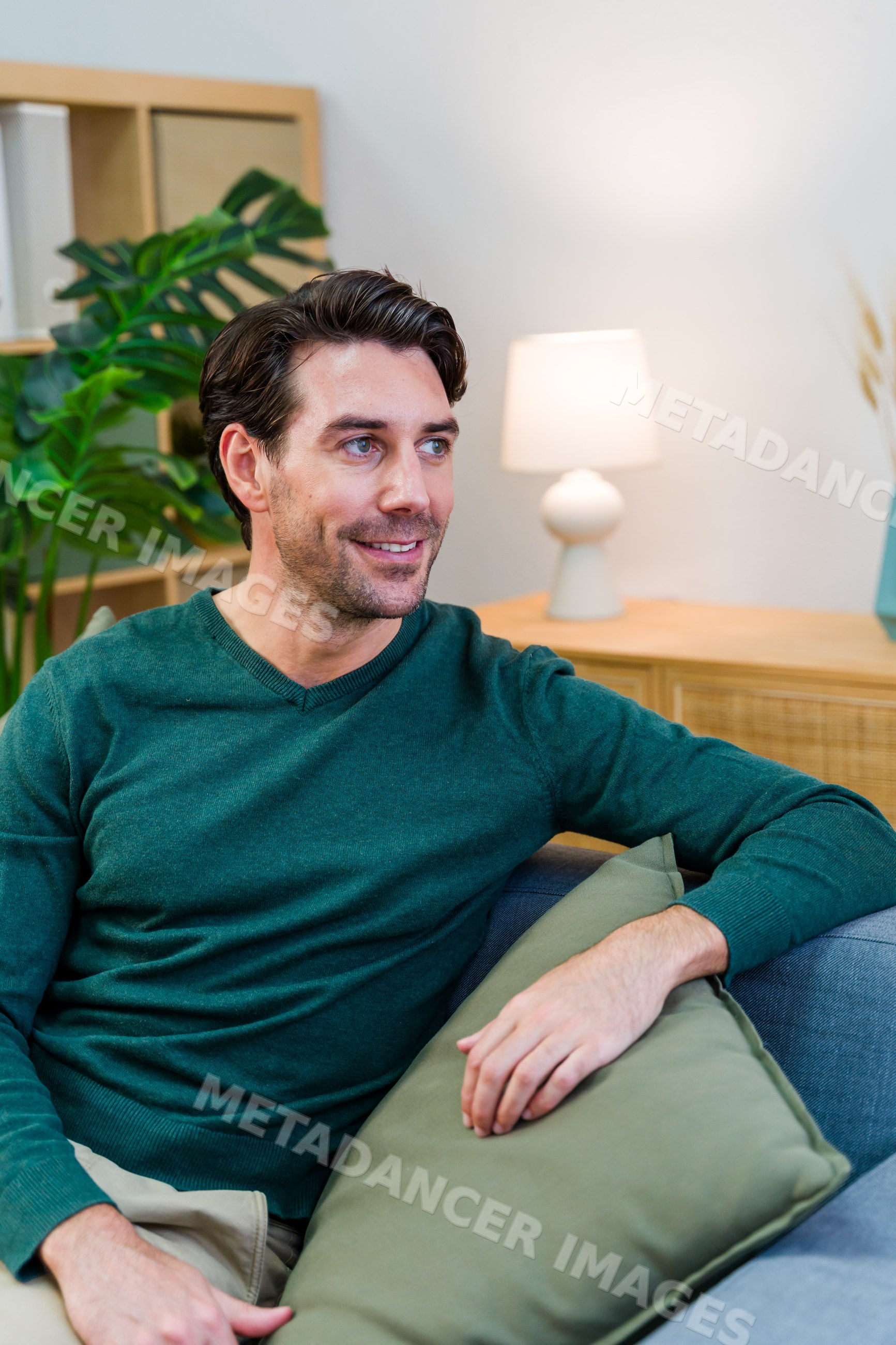 White man sitting on couch smiling in living room interior