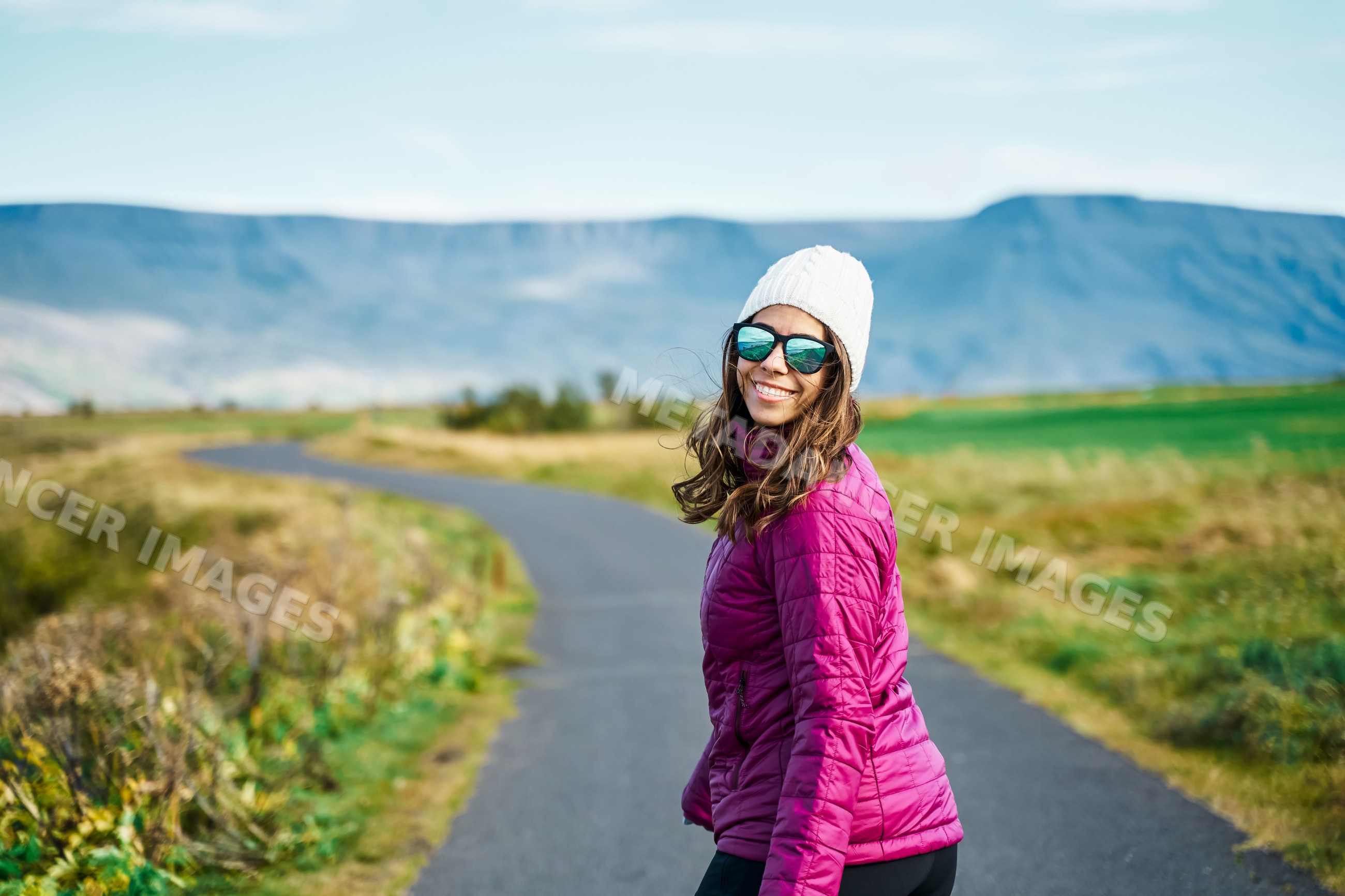 A white woman walking on a nature path with mountains