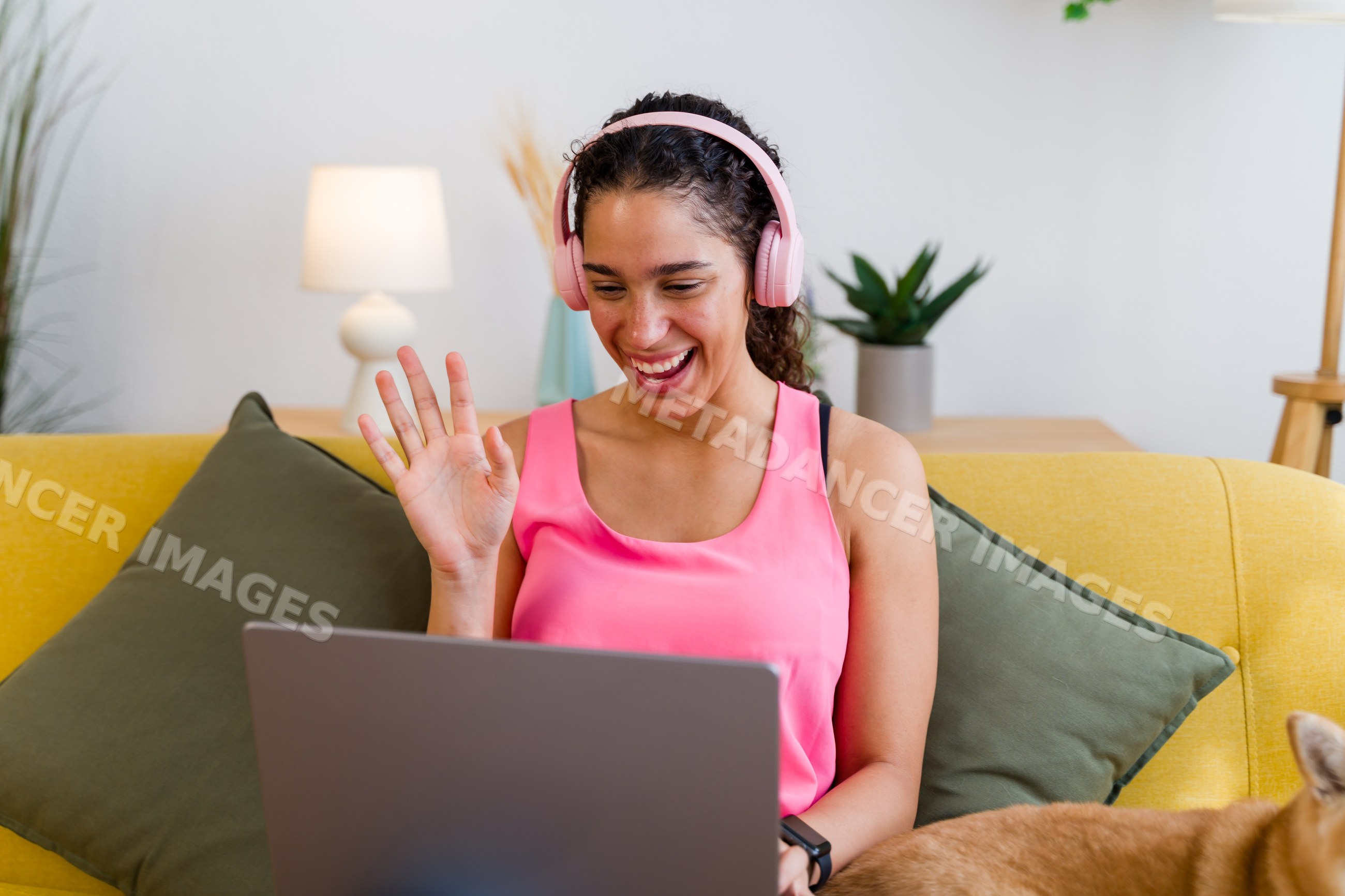 Hispanic Woman enjoying a video call at home on a yellow sofa