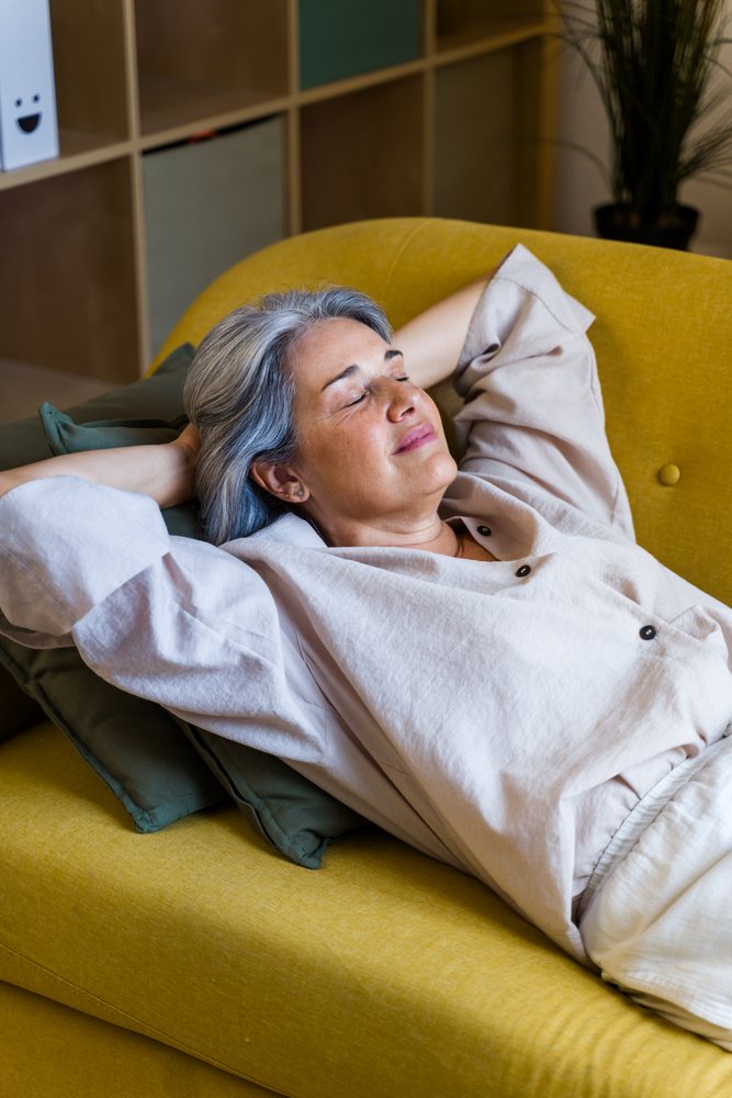 White woman relaxing peacefully on yellow sofa indoors