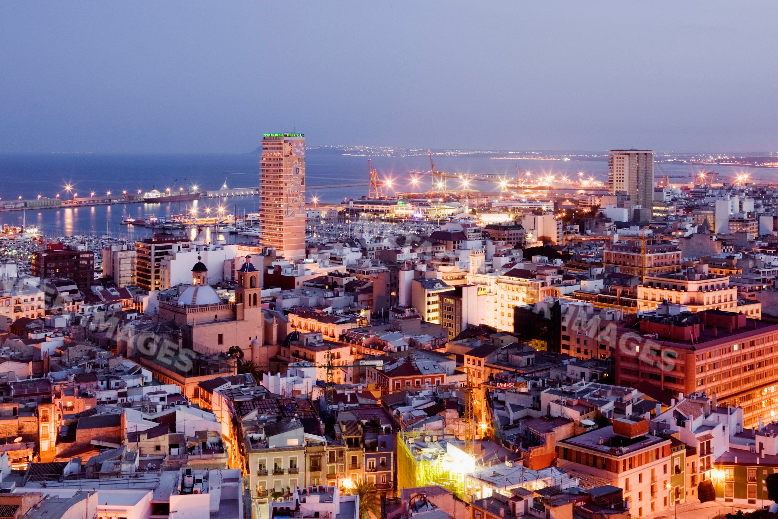 Costa blanca cityscape with harbor cranes and evening lights