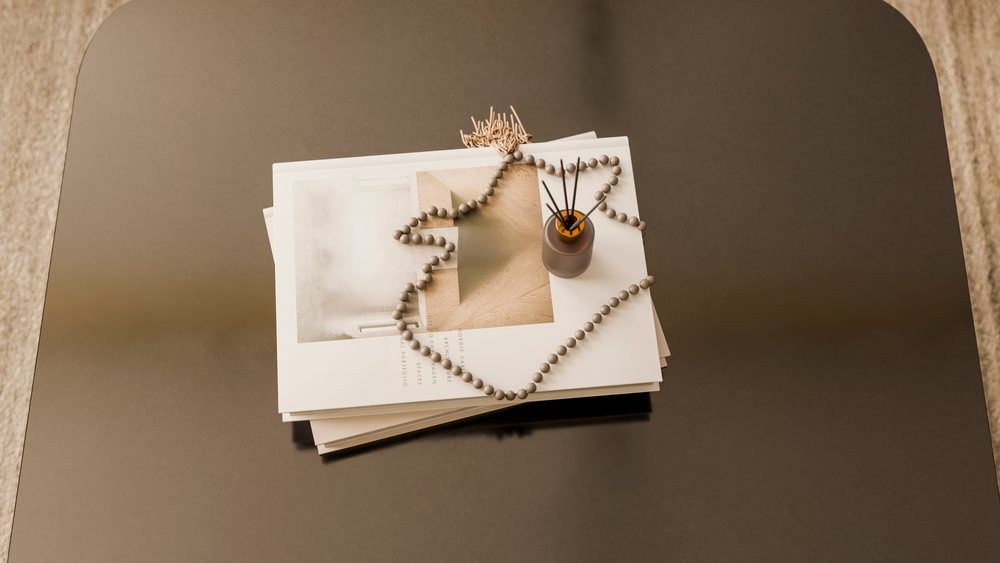 Stack of magazines with reed diffuser and beaded garland on table