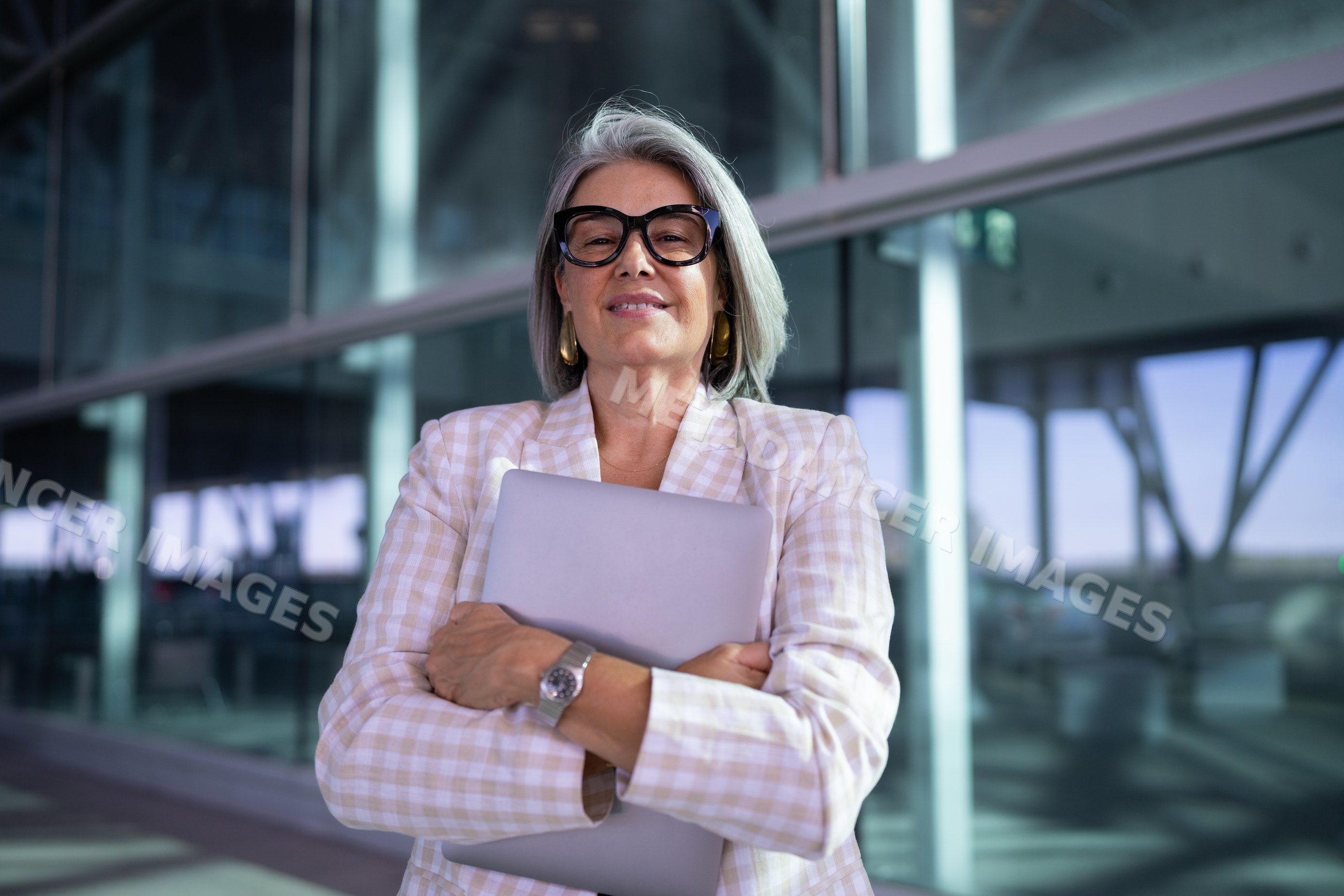 Businesswoman holding laptop outside modern glass building