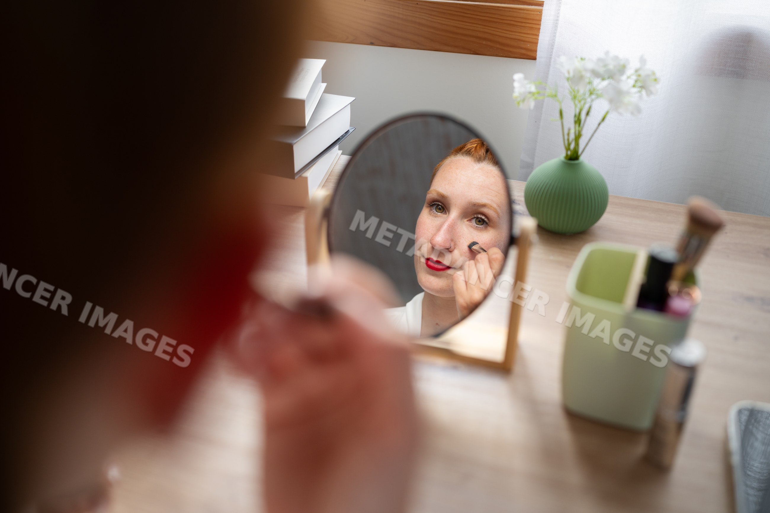 White Woman applying makeup at home in Galicia, Spain during working
