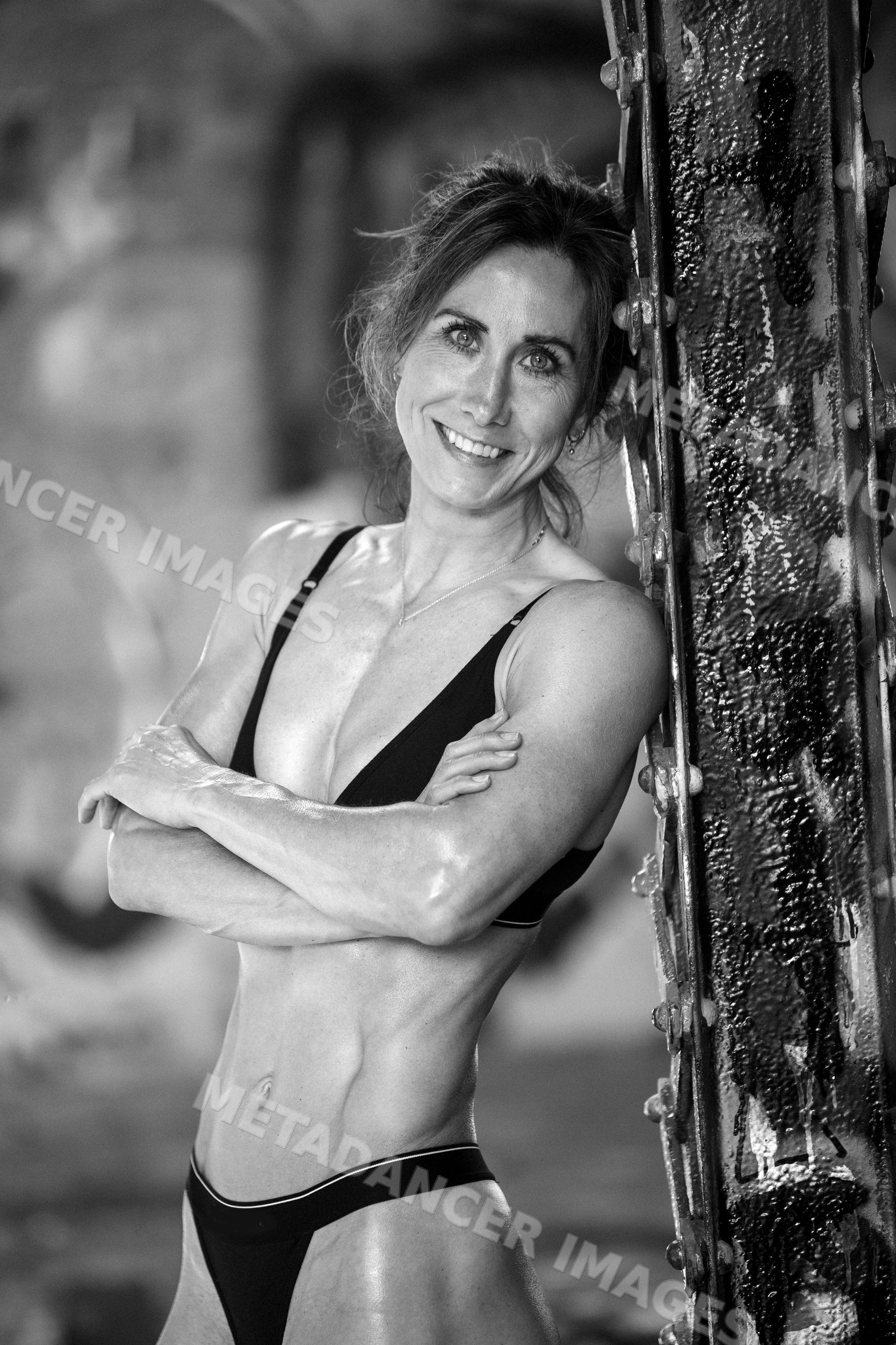 Fit white woman with muscular torso posing in urban setting