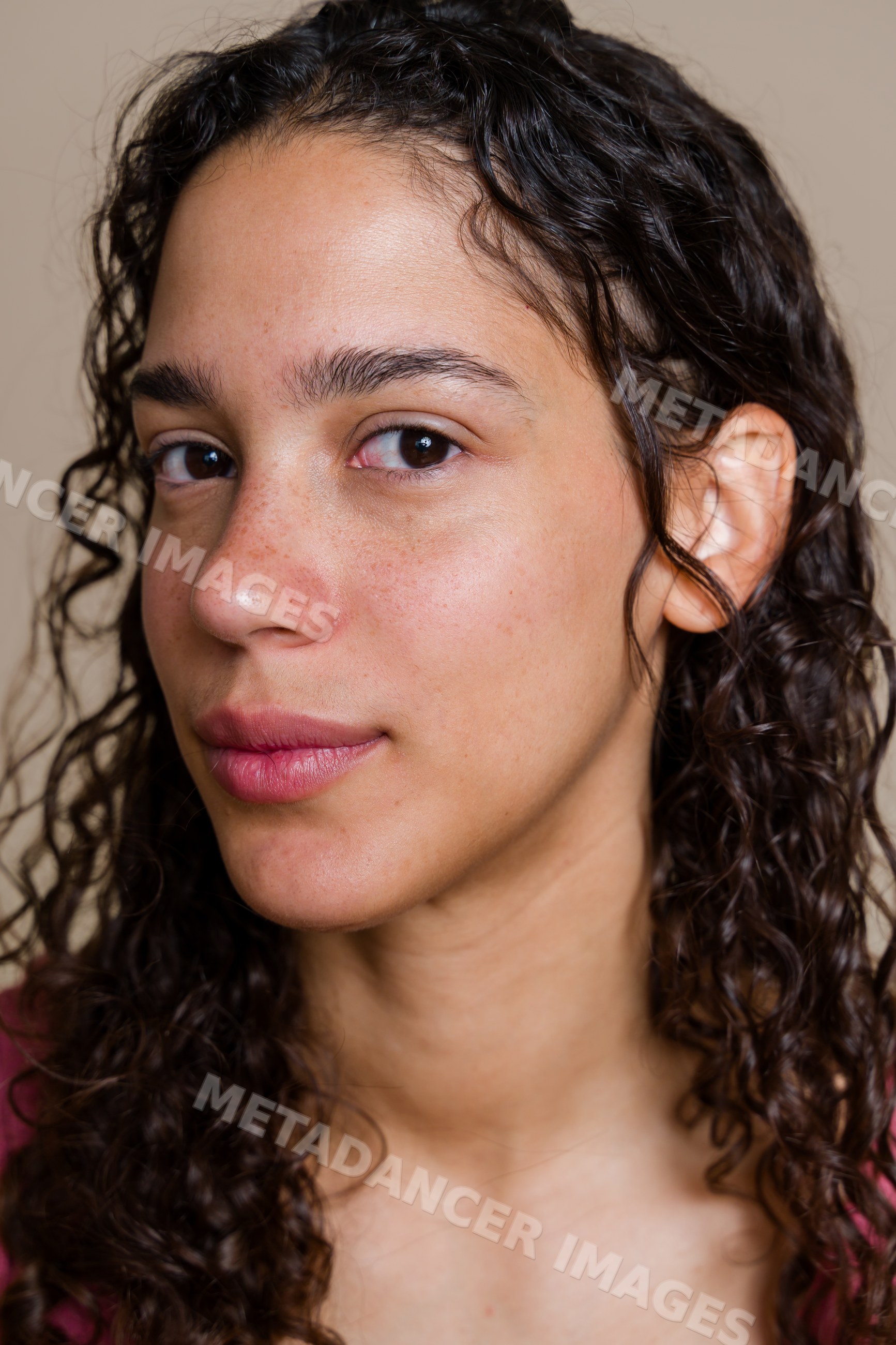 Hispanic woman with curly hair and freckles in a beauty shoot studio