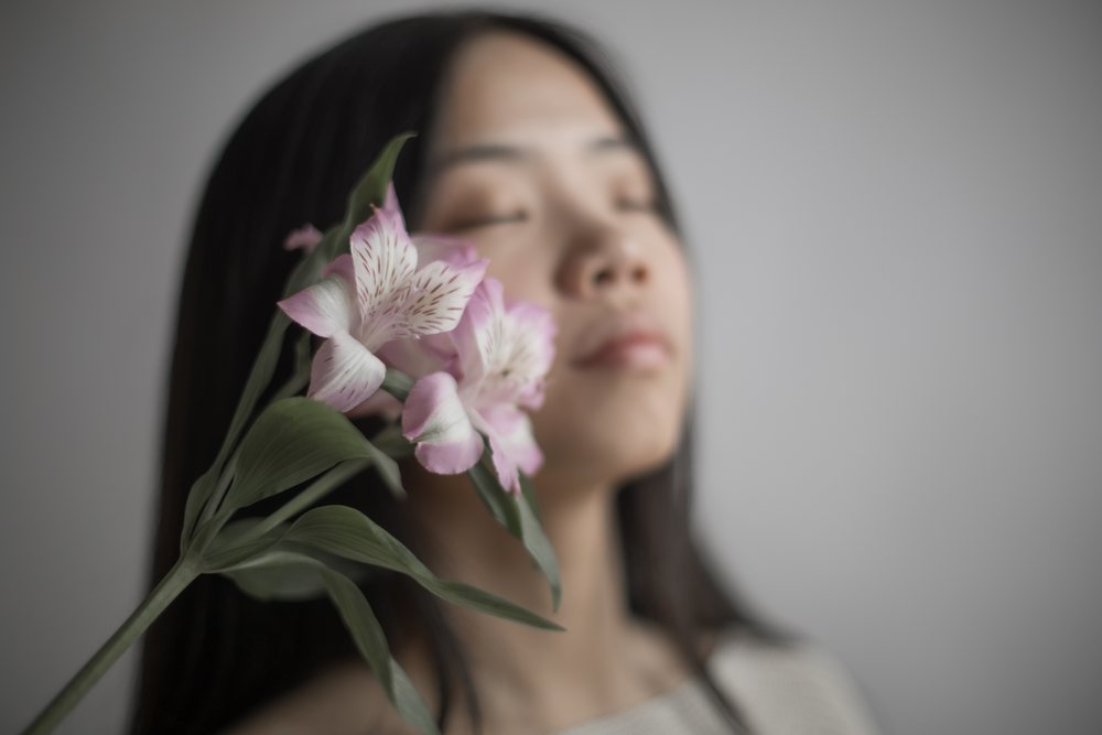 Emotional portrait of Southeast Asian woman with pink flower
