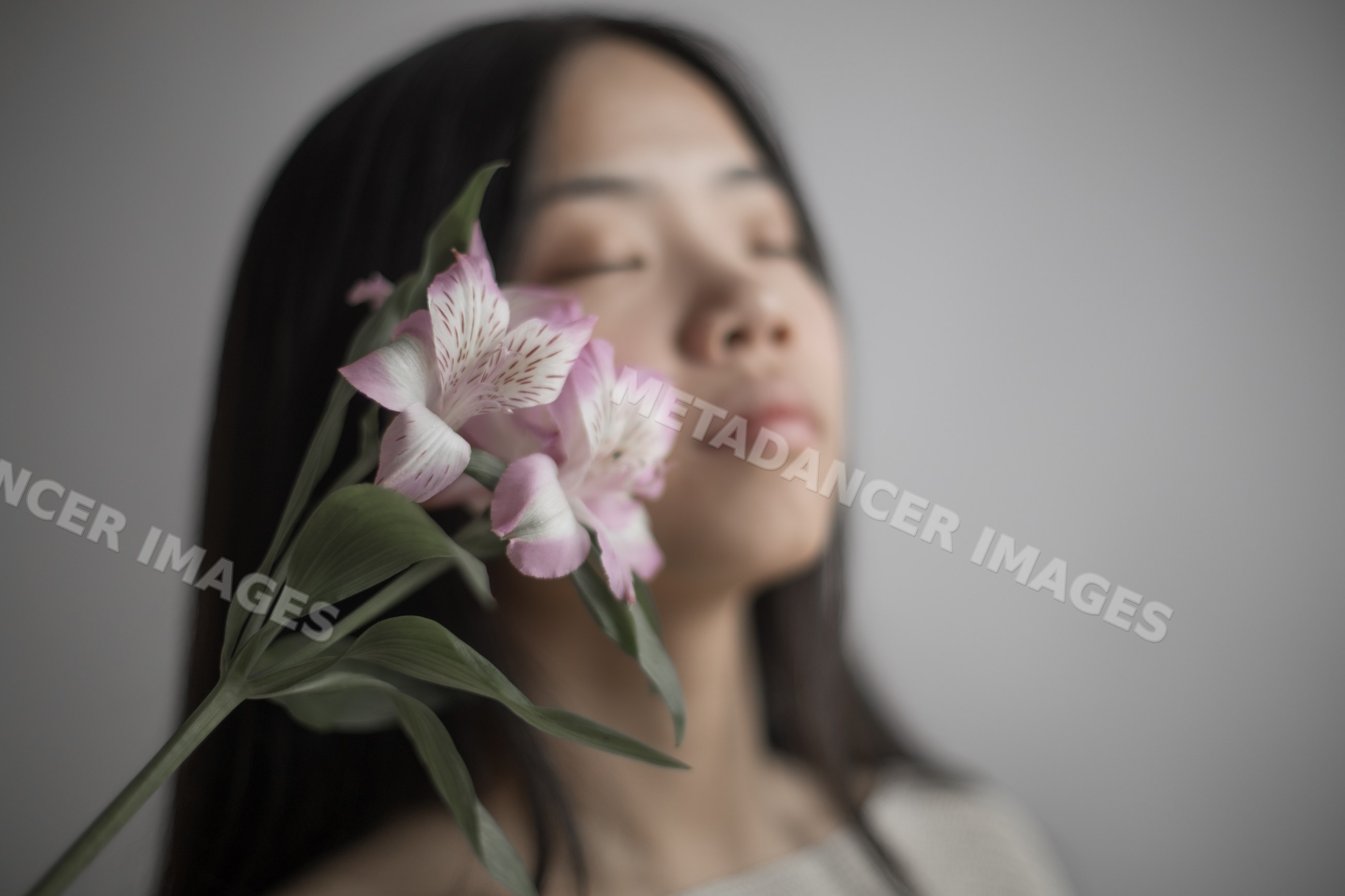 Emotional portrait of Southeast Asian woman with pink flower