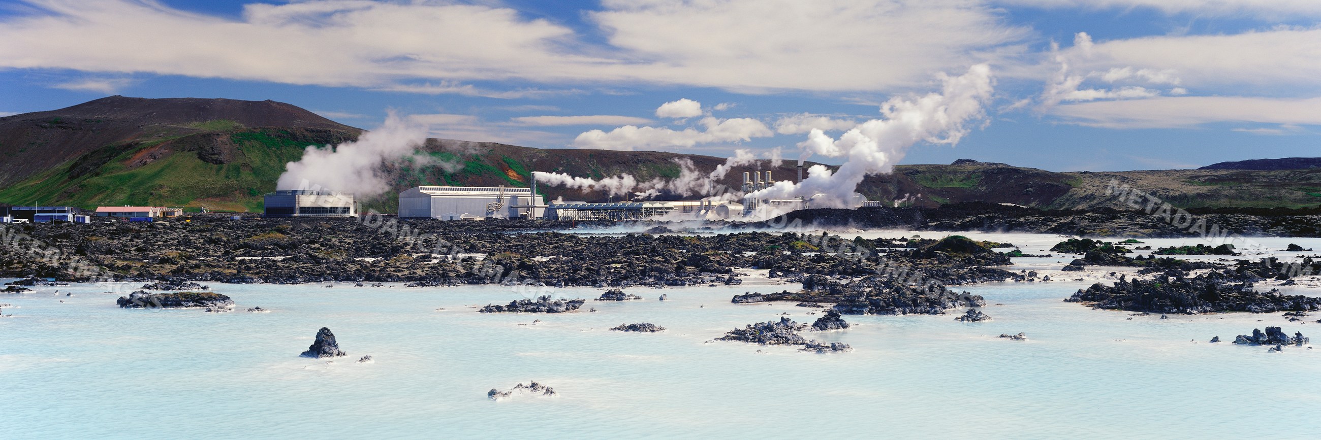 Steam rising from geothermal power plant in volcanic landscape