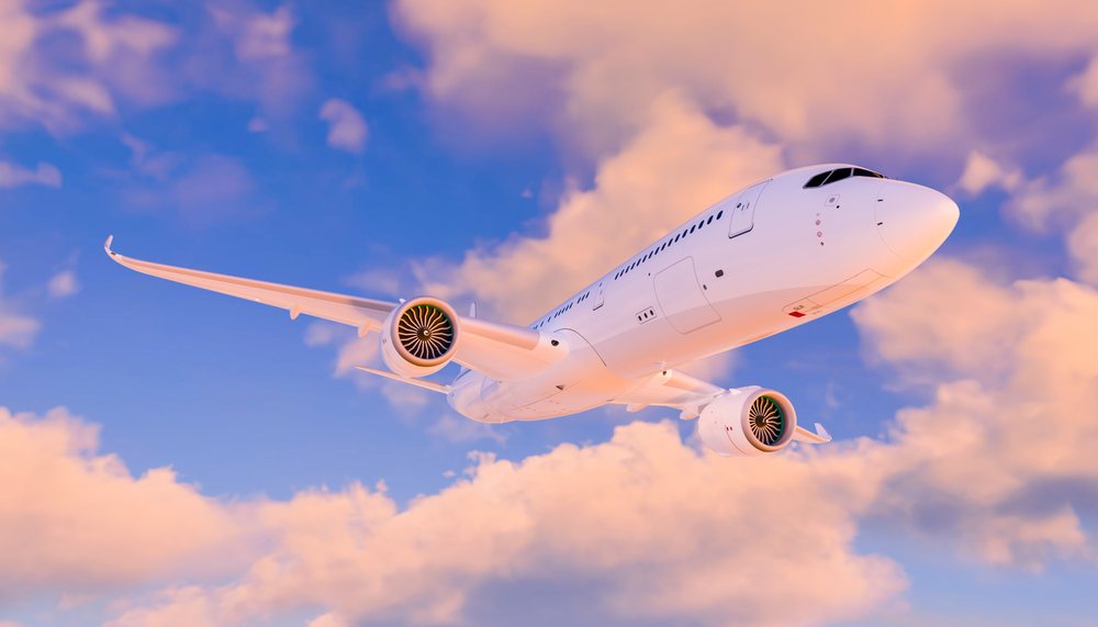 A commercial airplane flying through a blue sky with sunset clouds
