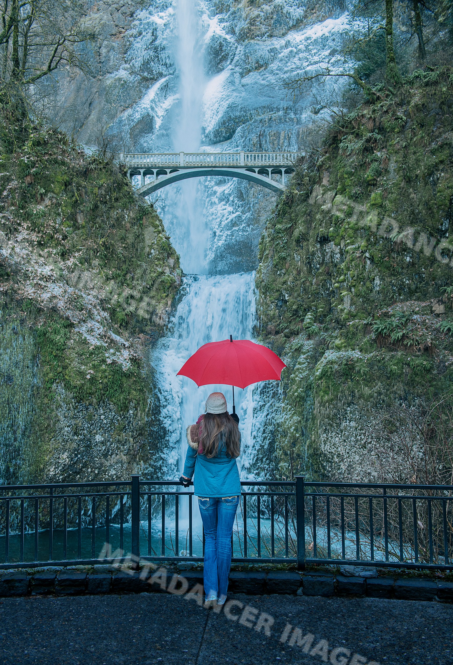 White woman with red umbrella viewing multnomah falls and pedestrian