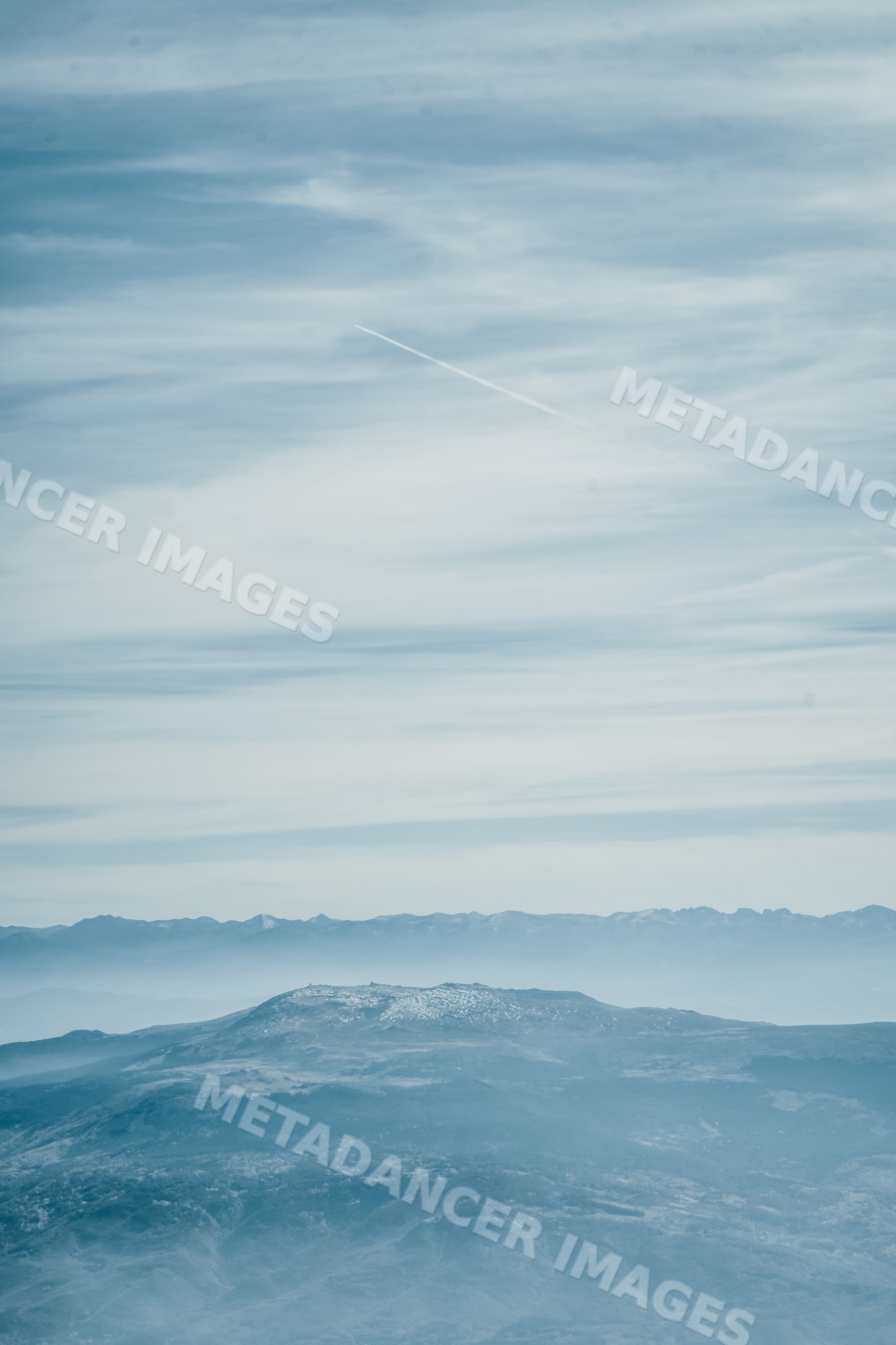 Mountain landscape with distant mountain range beneath cloudy sky