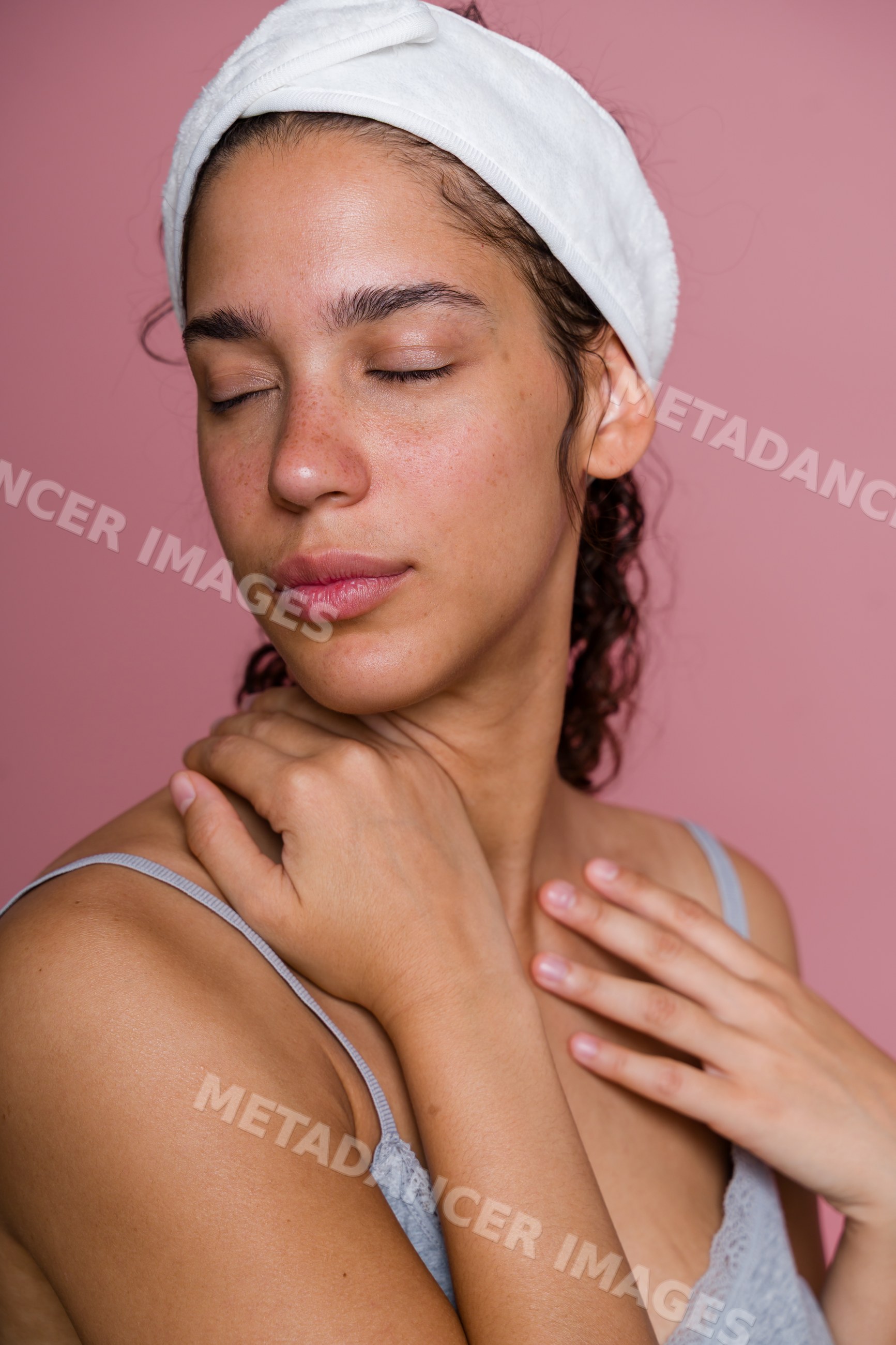 Hispanic woman with closed eyes and headband touching shoulder