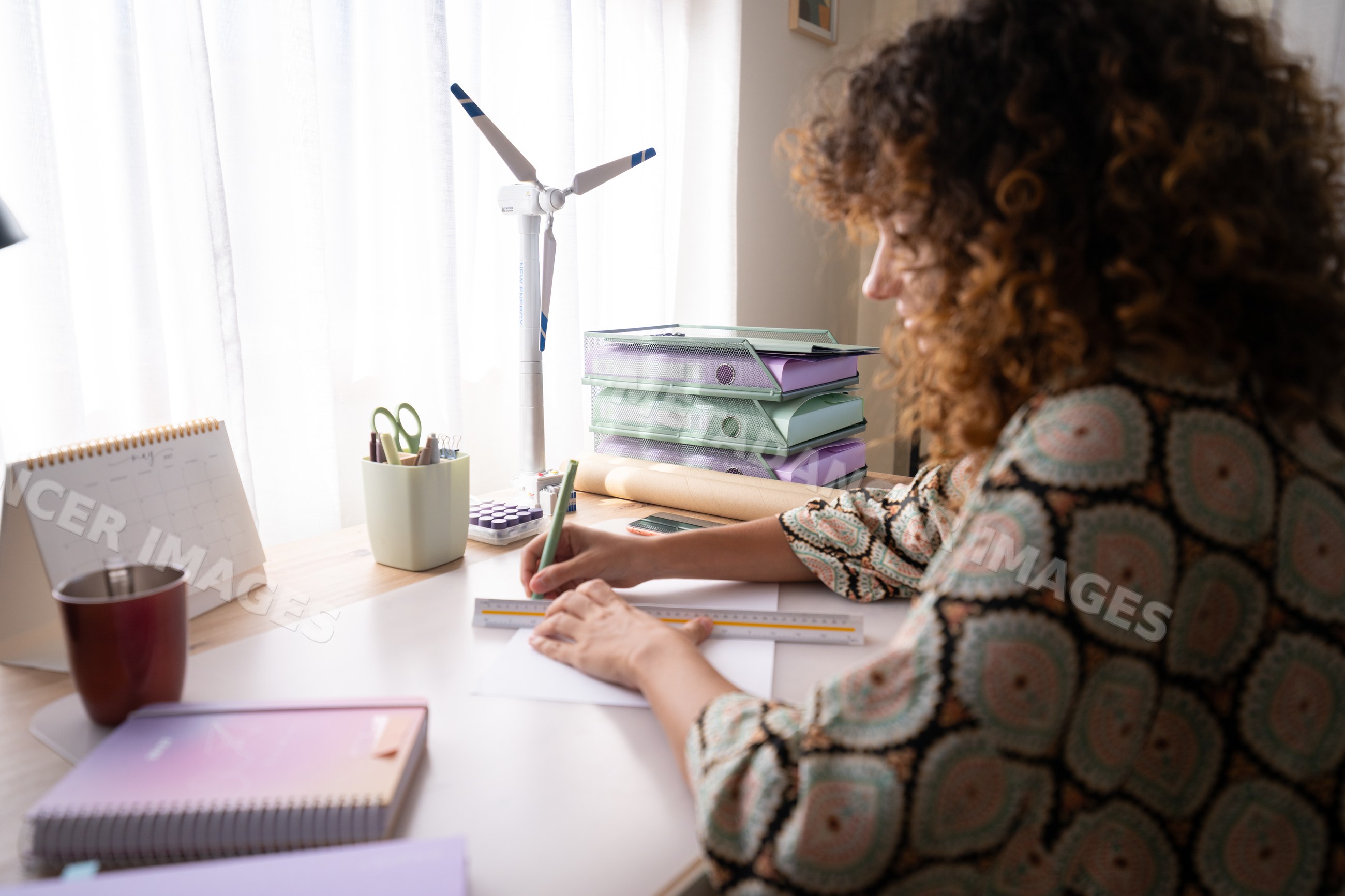 White woman writing at an organized desk with natural light in a home