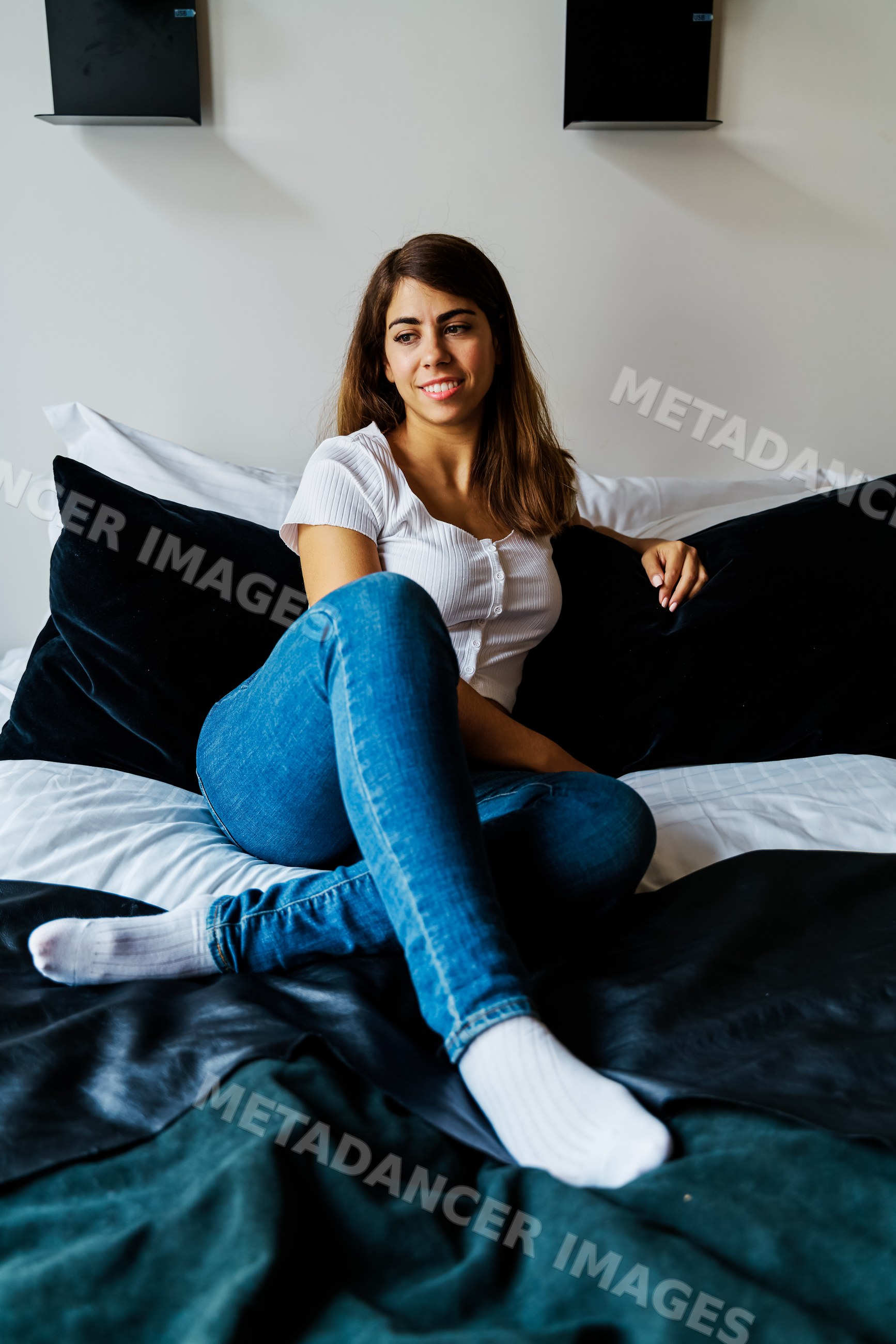A young woman sitting comfortably on a bed in a modern indoor setting