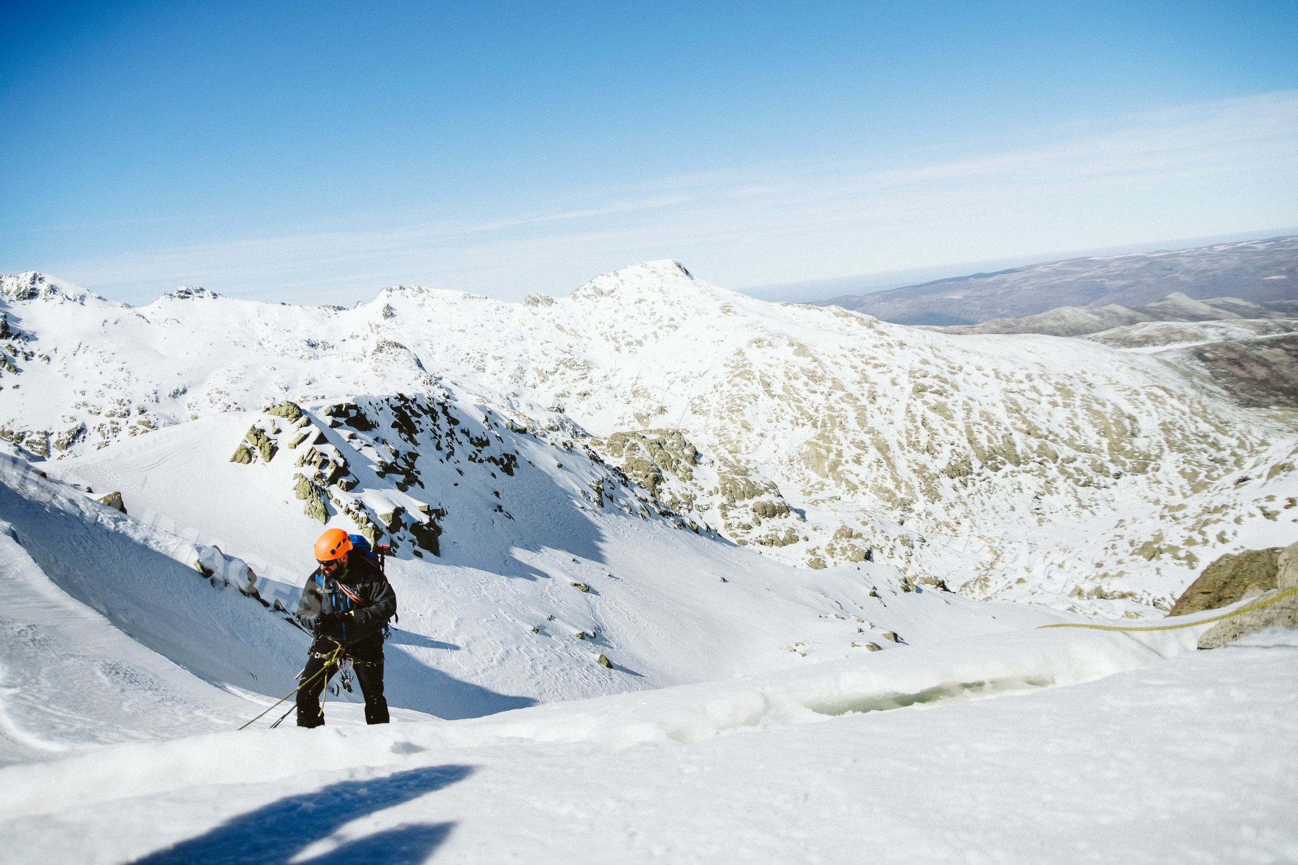 Mountaineer climbing snowy mountain slope in Spain landscape
