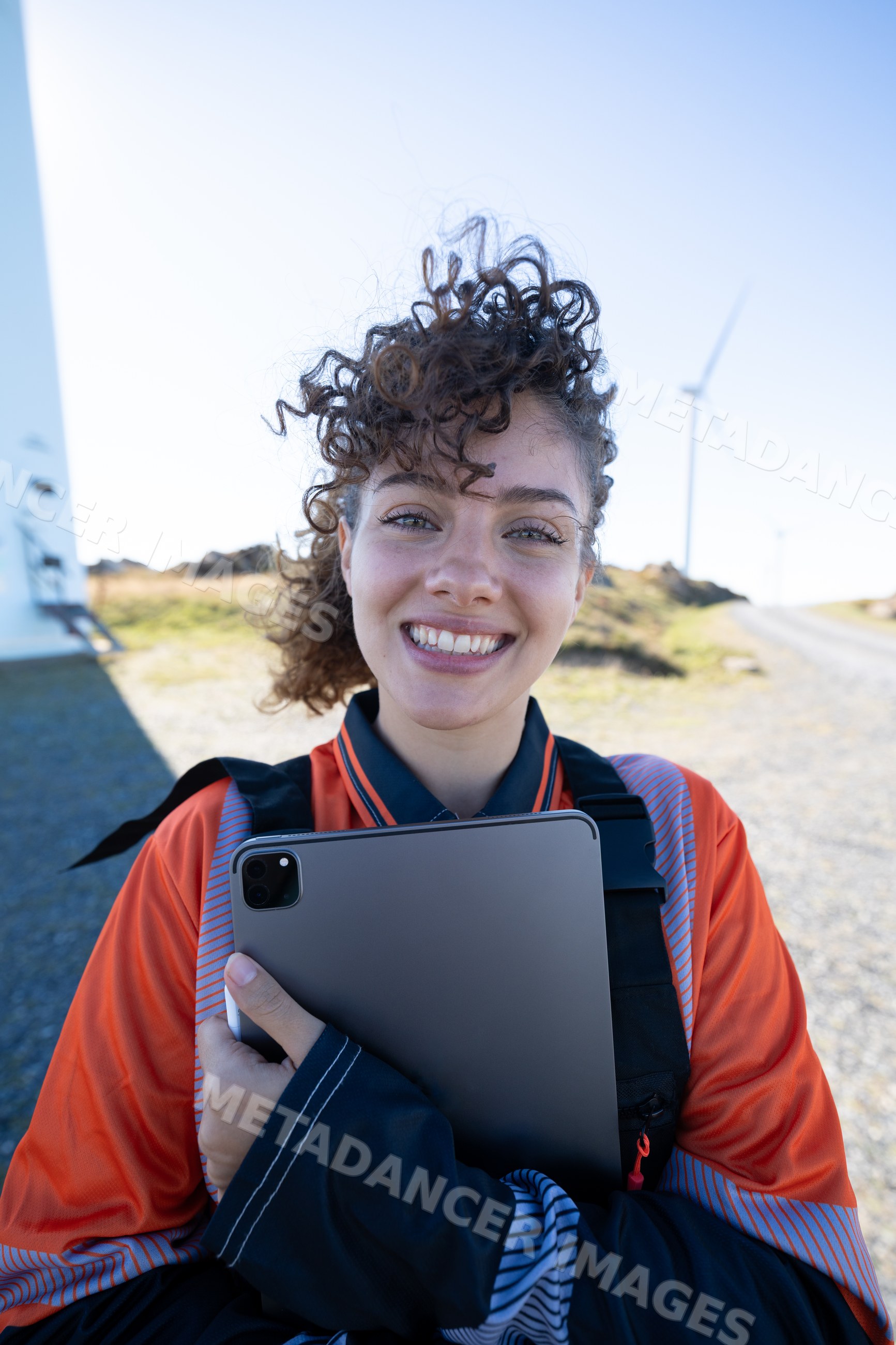 White woman holding tablet with wind turbines