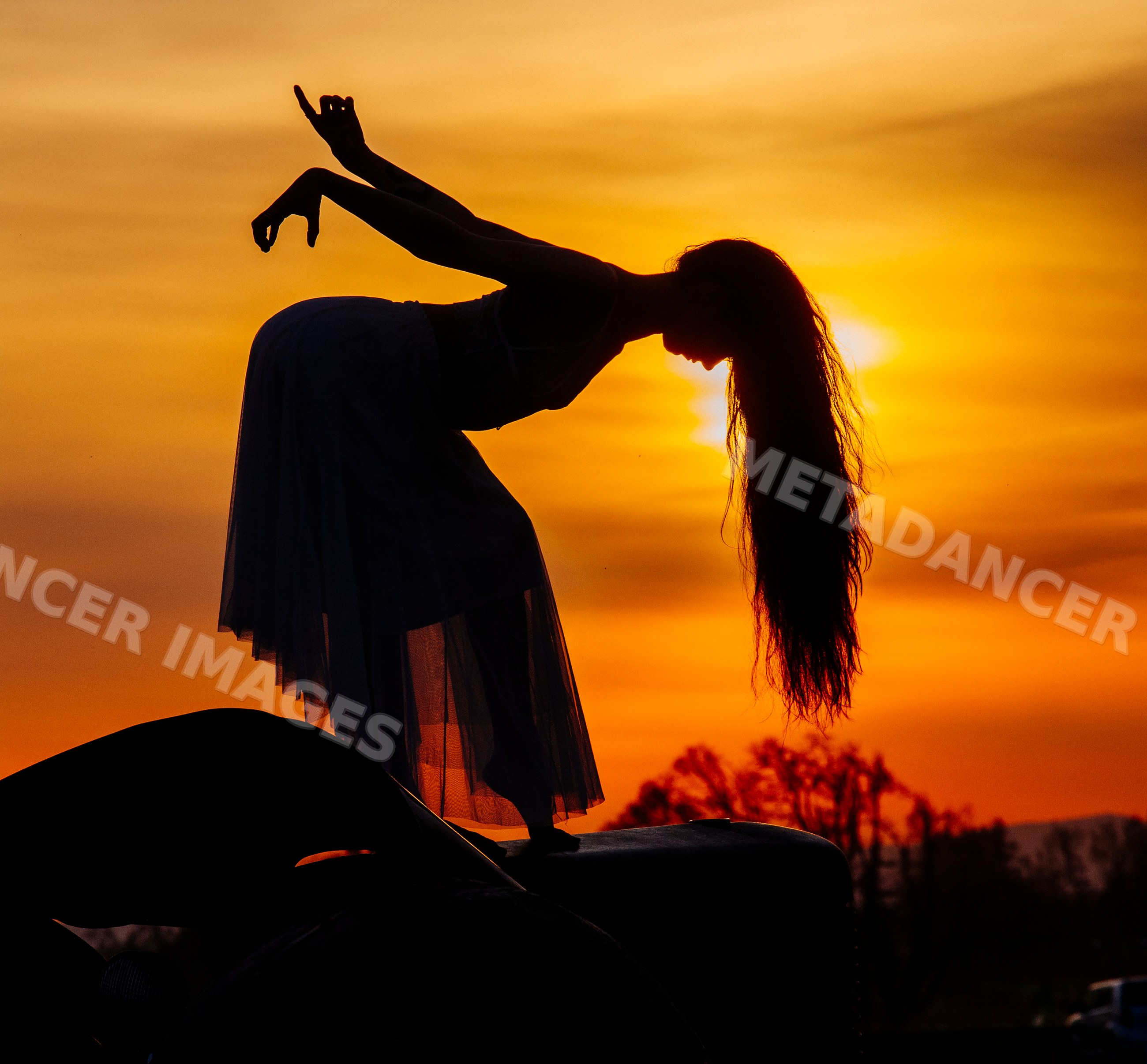 White dancer silhouette performing elegant pose at sunset outdoors