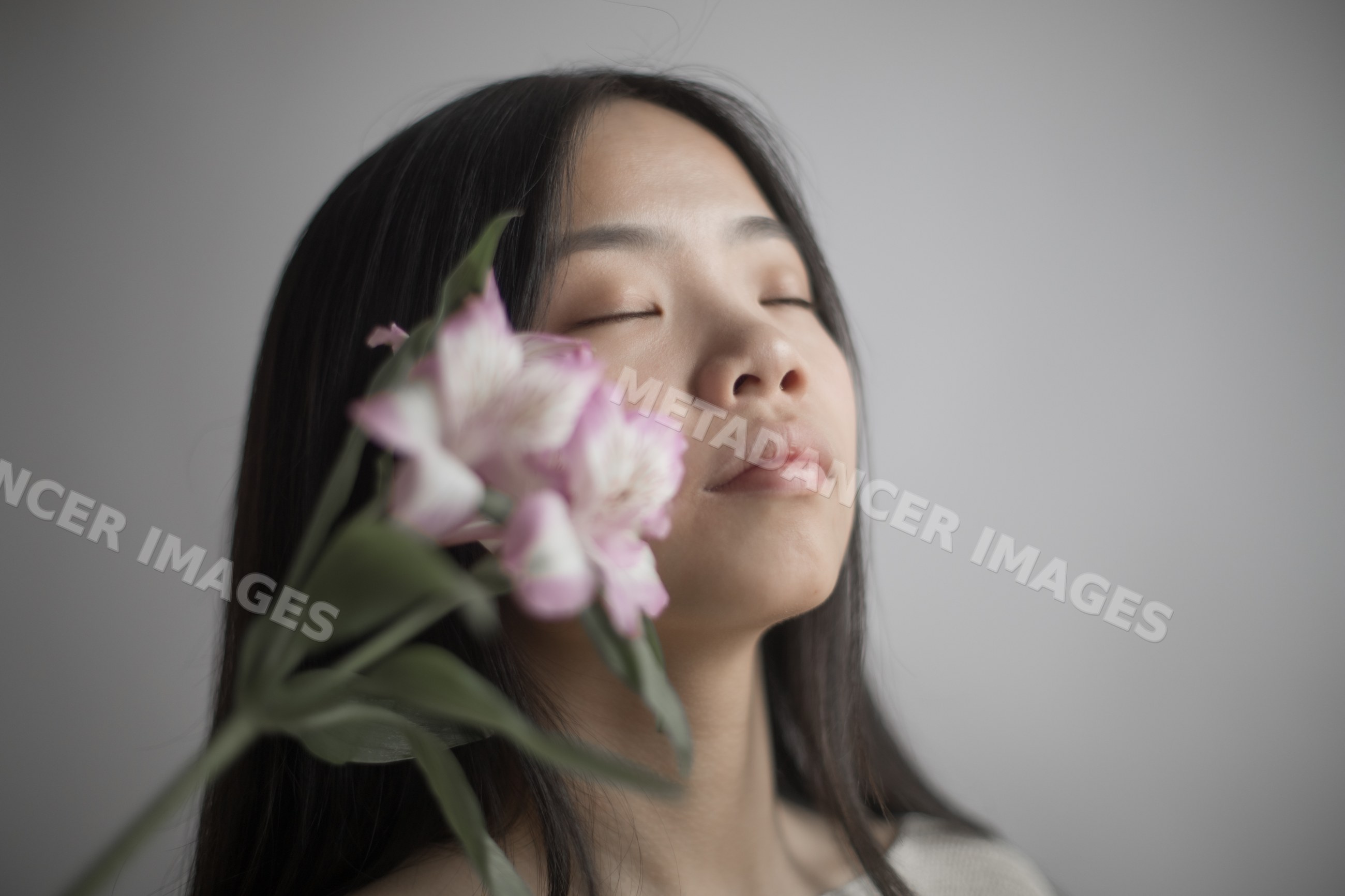 Portrait of Southeast Asian woman with closed eyes holding pink