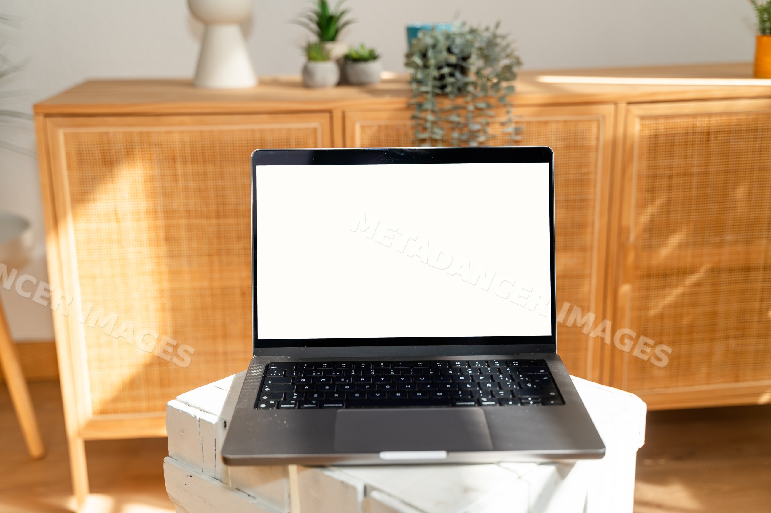 Laptop computer with blank screen on wooden table in modern interior