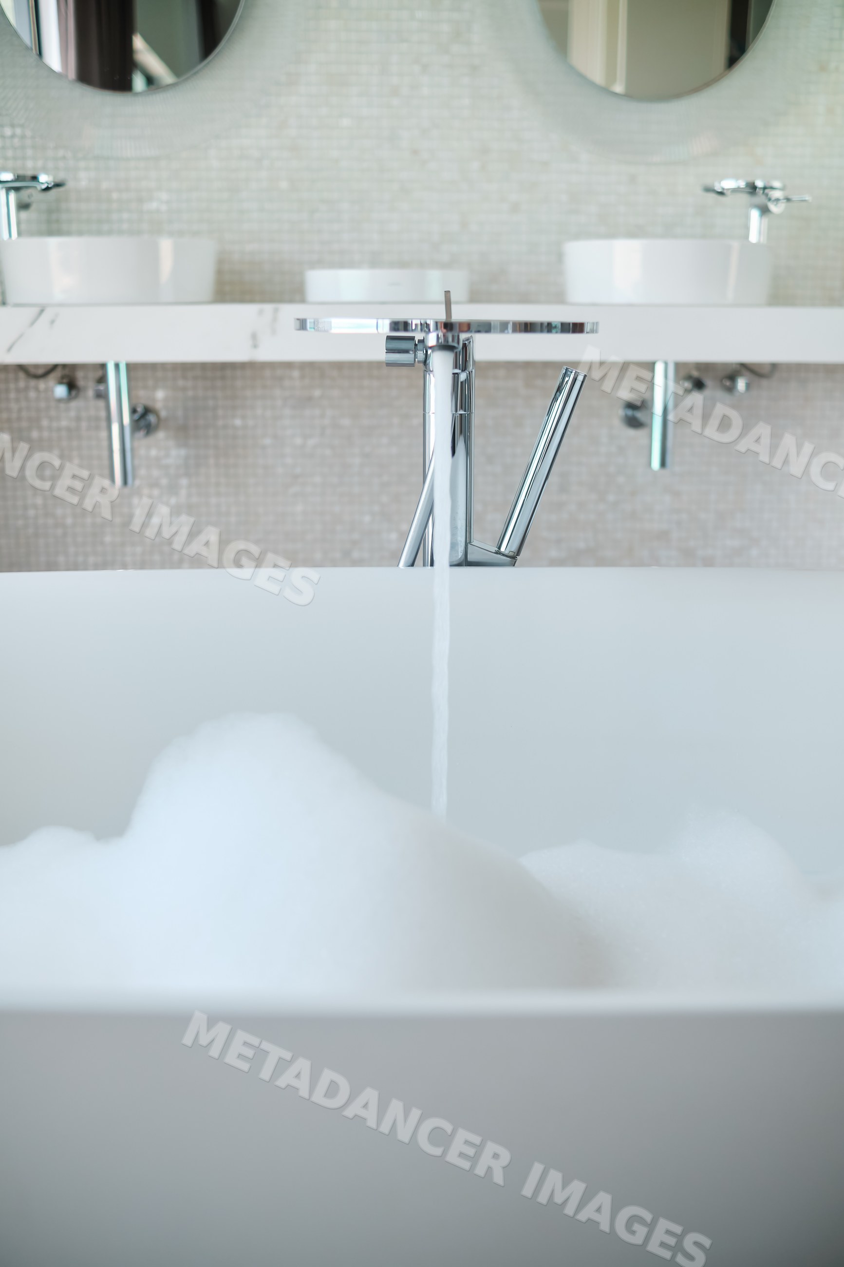 A modern bathroom bathtub filling with foamy bath water