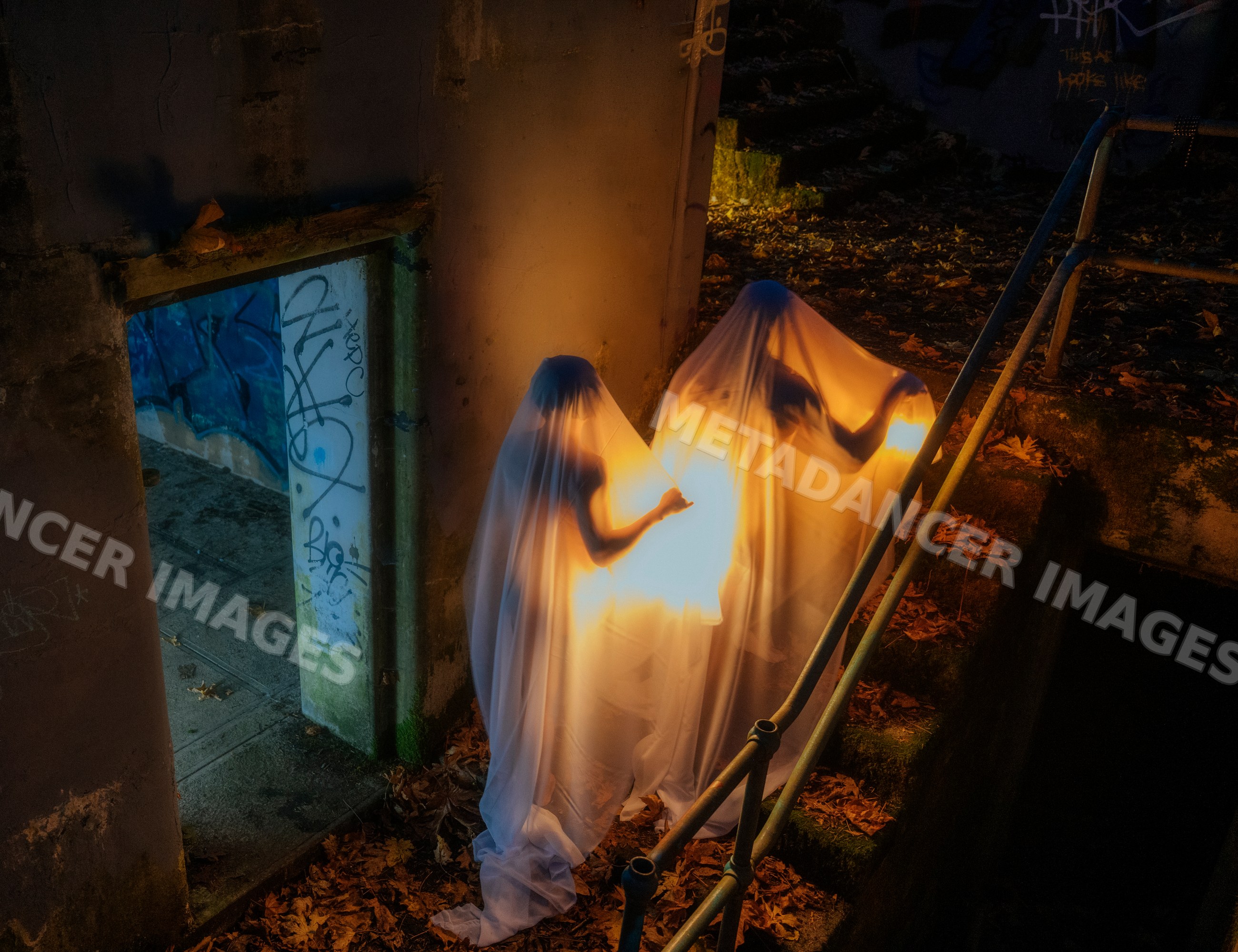 Ghostly figures illuminated on dark stairway with autumn leaves